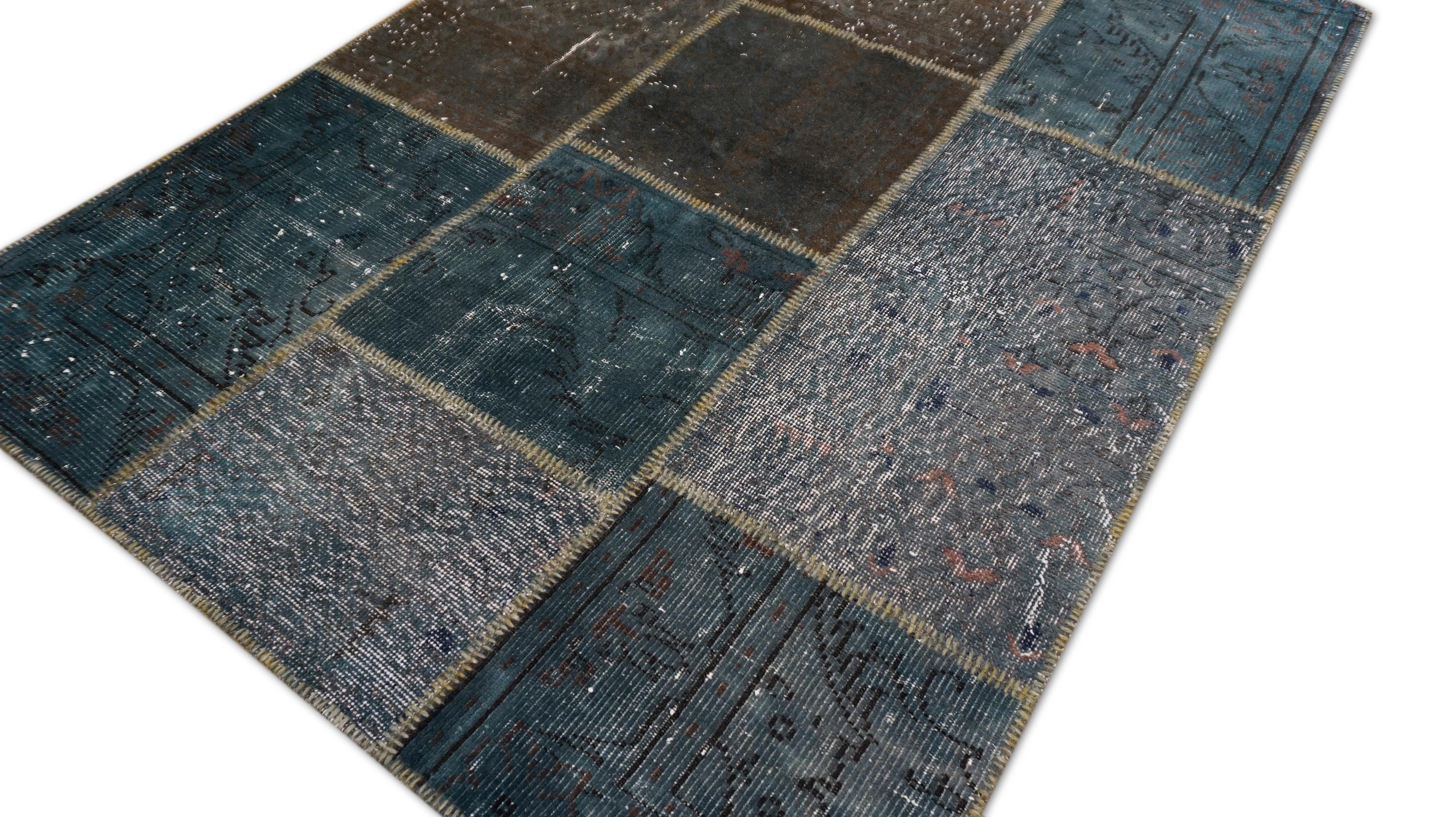 Questo tappeto patchwork in lana, tessuto a mano, presenta una sofisticata tavolozza di toni blu profondo, ardesia, grigio e verde acqua. Realizzato meticolosamente con tappeti d'epoca recuperati, ogni segmento è stato sovratinto e cucito a mano per