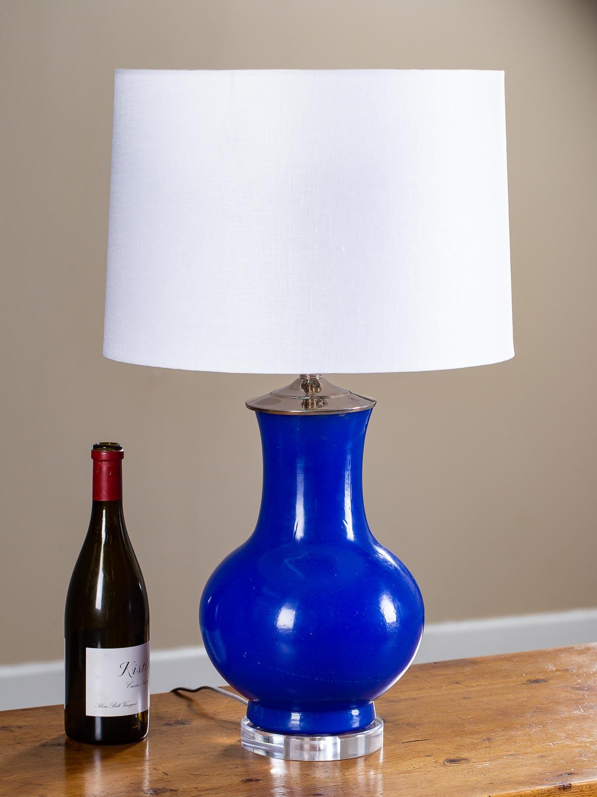 A luscious modern poured blue glass vase lamp mounted as a custom lamp with a circular Lucite base and wired for American electricity. The timeless Silhouette of the vase echoes those seen in ancient China while the translucent blue glass is