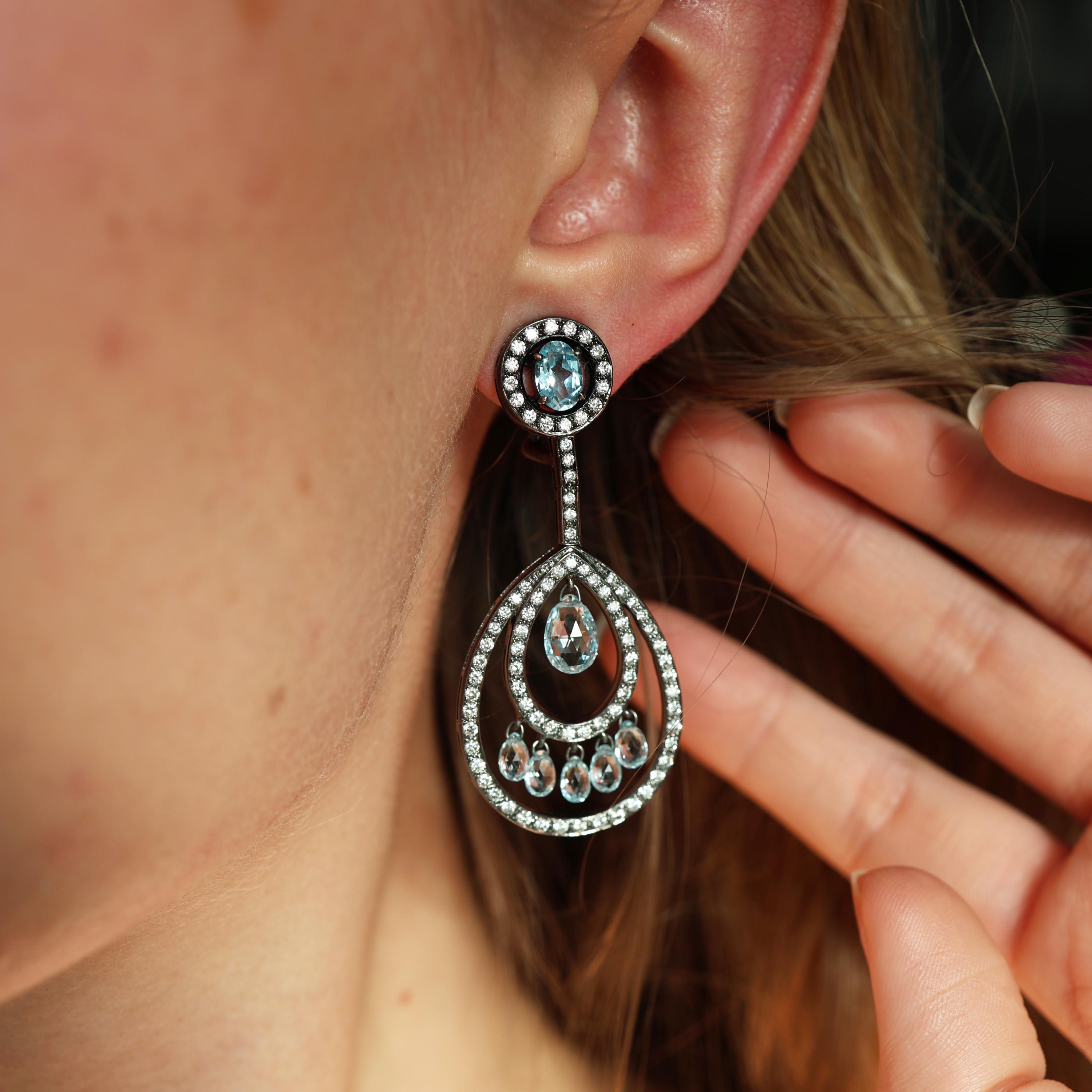 Coppia di orecchini a goccia con topazio blu e diamanti, comprendenti top con un diamante ovale sfaccettato a forma di pera, circondato da un cerchio di diamanti rotondi taglio brillante, con una fila di diamanti rotondi taglio brillante, che si
