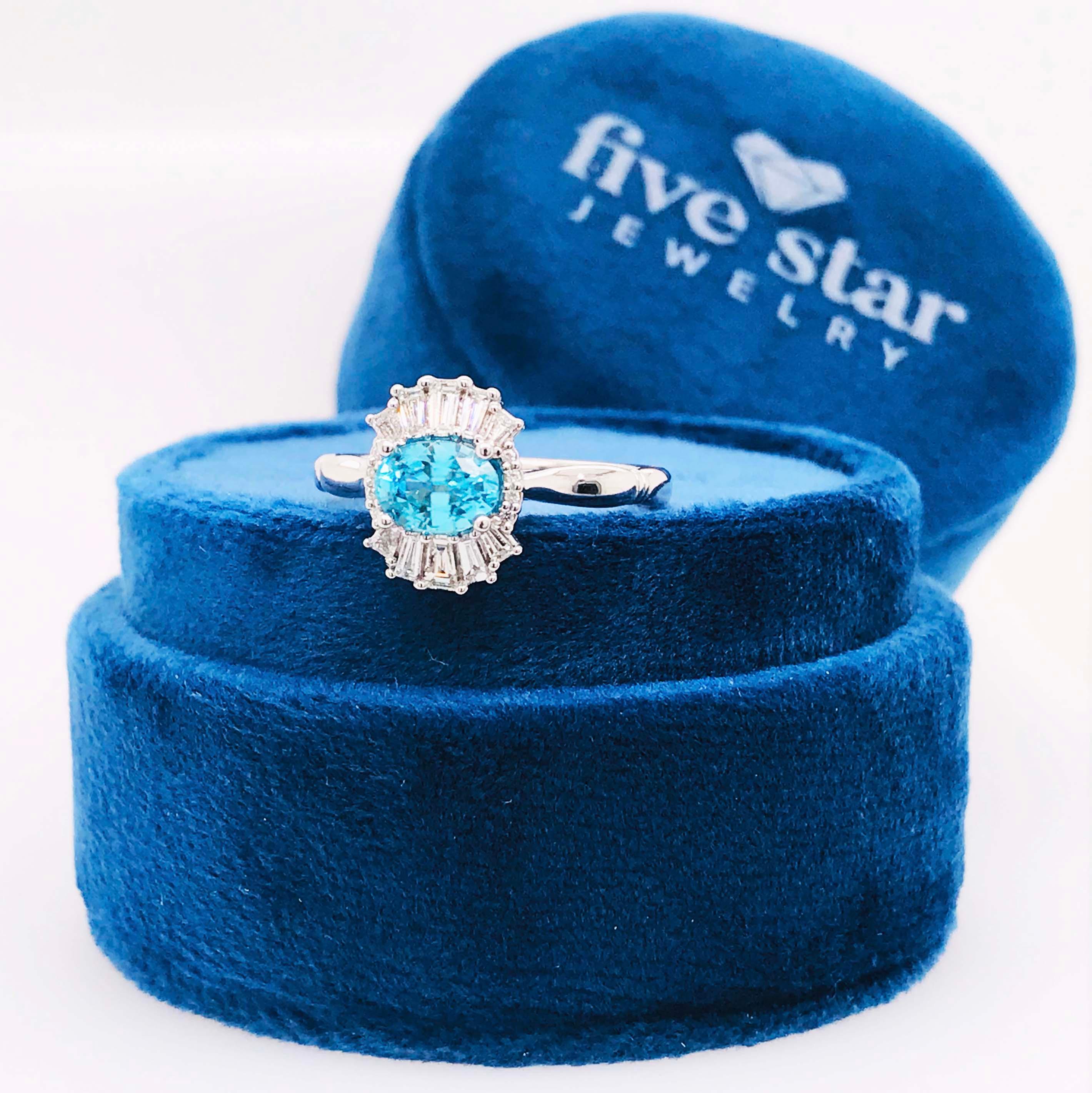 This striking blue zircon and diamond ring is an unusual and gorgeous design with genuine natural gemstones. The center of this gorgeous piece is a bright blue oval zircon measuring 7 mm long by 5mm wide, set east to west for a contemporary style on