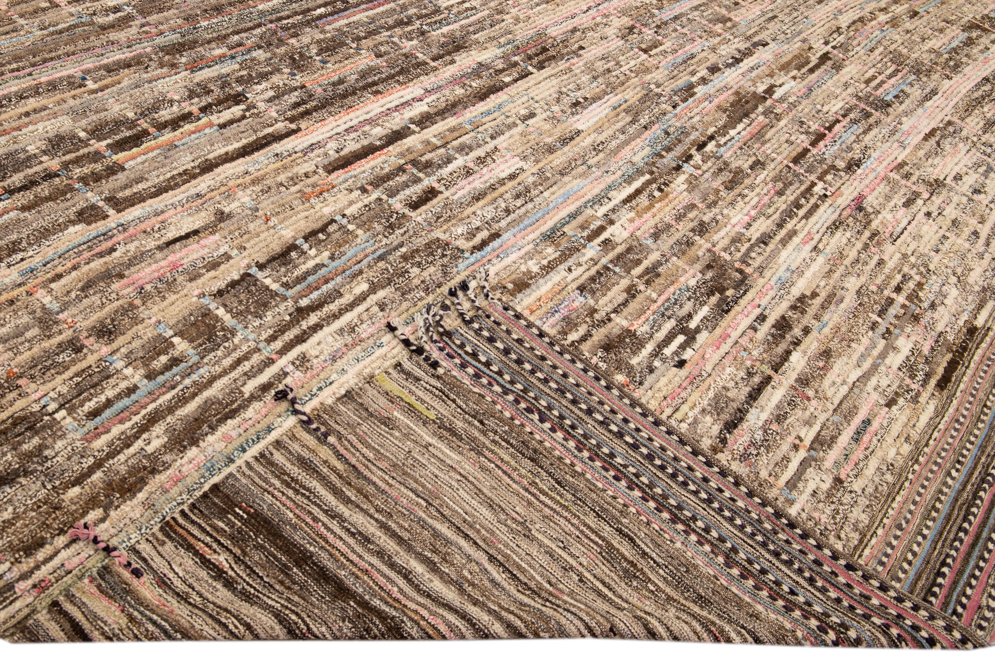 Wunderschöner, handgefertigter Wollteppich im marokkanischen Stil mit einem beigen und braunen Feld. Dieser moderne Teppich mit orangefarbenen, blauen, roten und gelben Akzenten und beigen Fransen hat ein wunderschönes All-Over-Design im