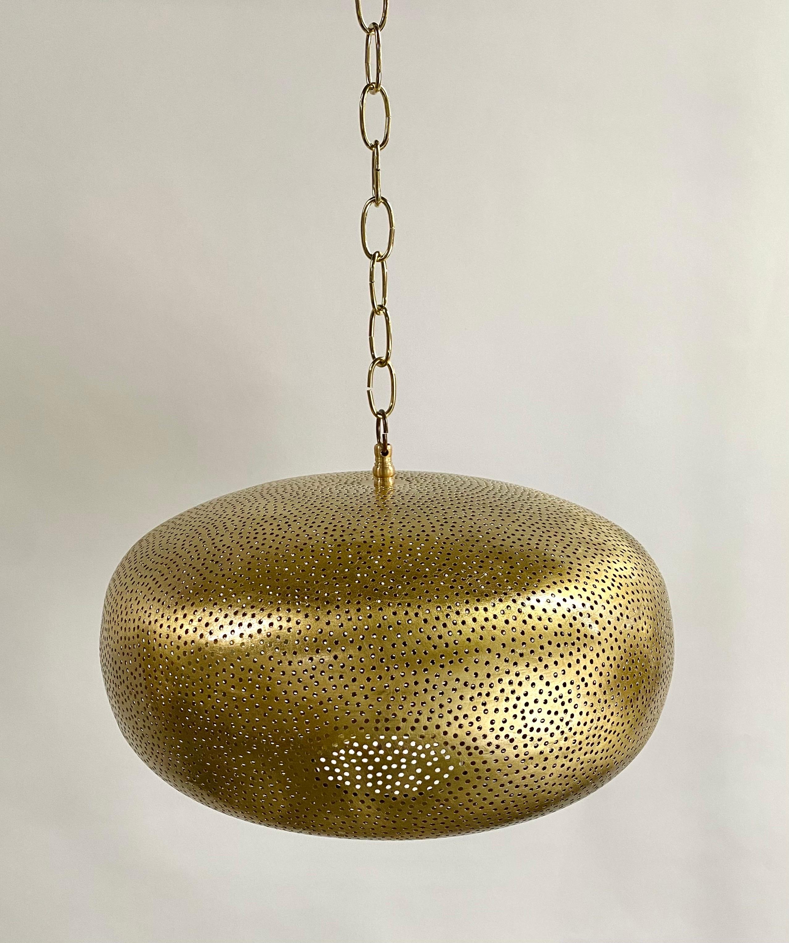 A modern / boho chic brass pendant or chandelier. Featuring hand-tooled brass and further enhanced with an oval retro shape, the pendant or lantern produces a soft ambient lighting perfect for elevating mood and complementing aesthetic harmony,