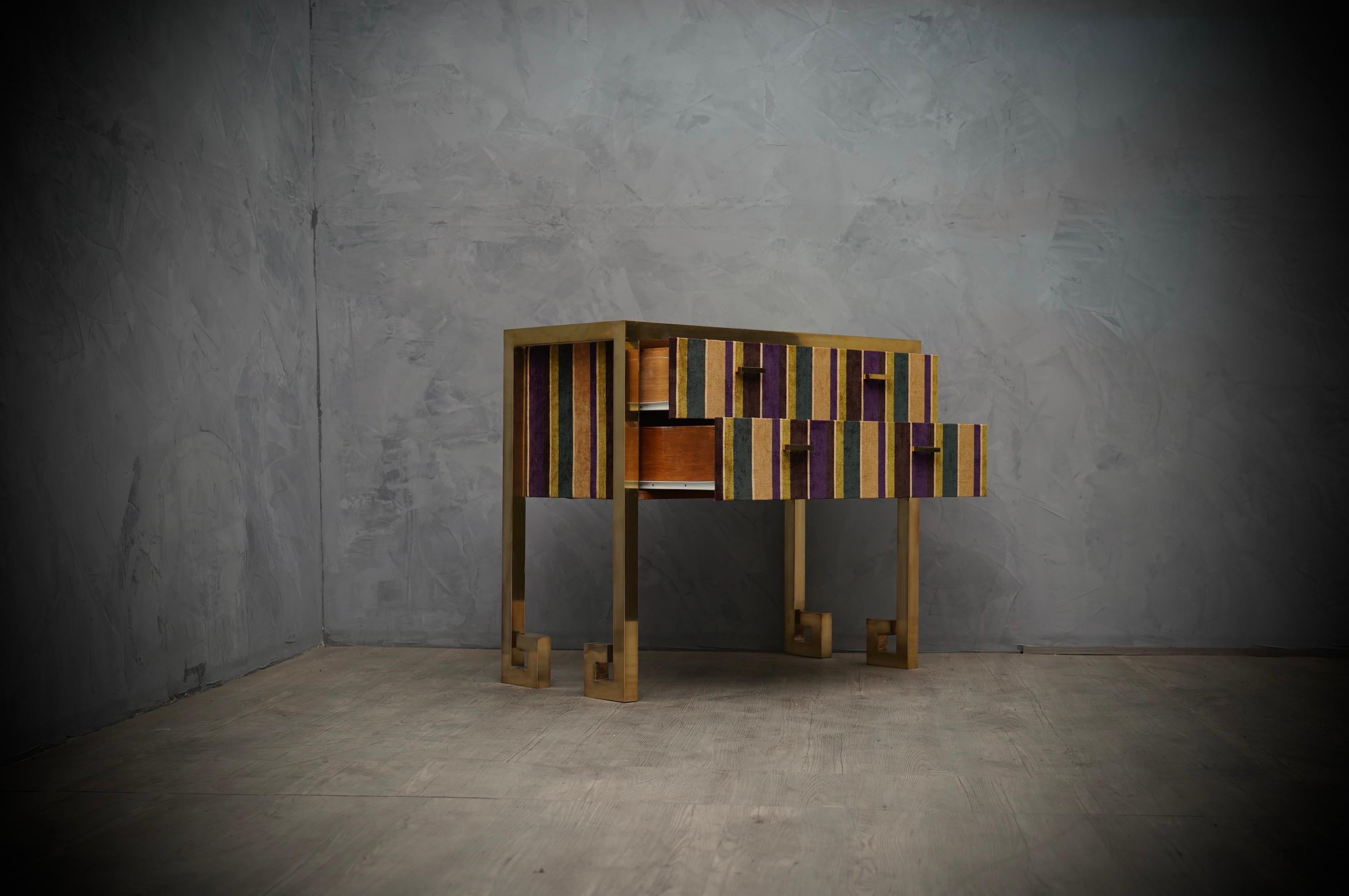 Glamor and bright colors dresser, due to the choice of refined materials.

The whole external structure is in polished brass, while the inside of the body is in wood covered in striped velvet, in shades of green and brown. The brass structure form a