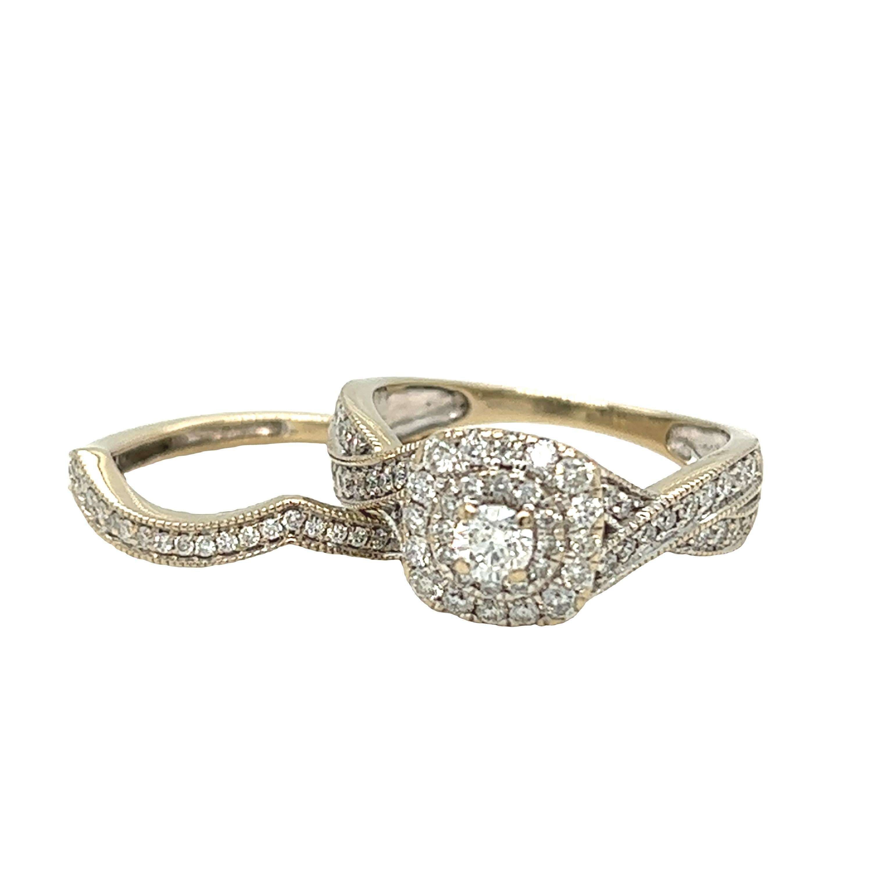 An intricately designed engagement ring and wedding band set by Modern bride. At center is a round brilliant cut diamond set in a diamond encrusted cushion double halo finished with milgrain edges. The halo is attached to a twisted shank accented