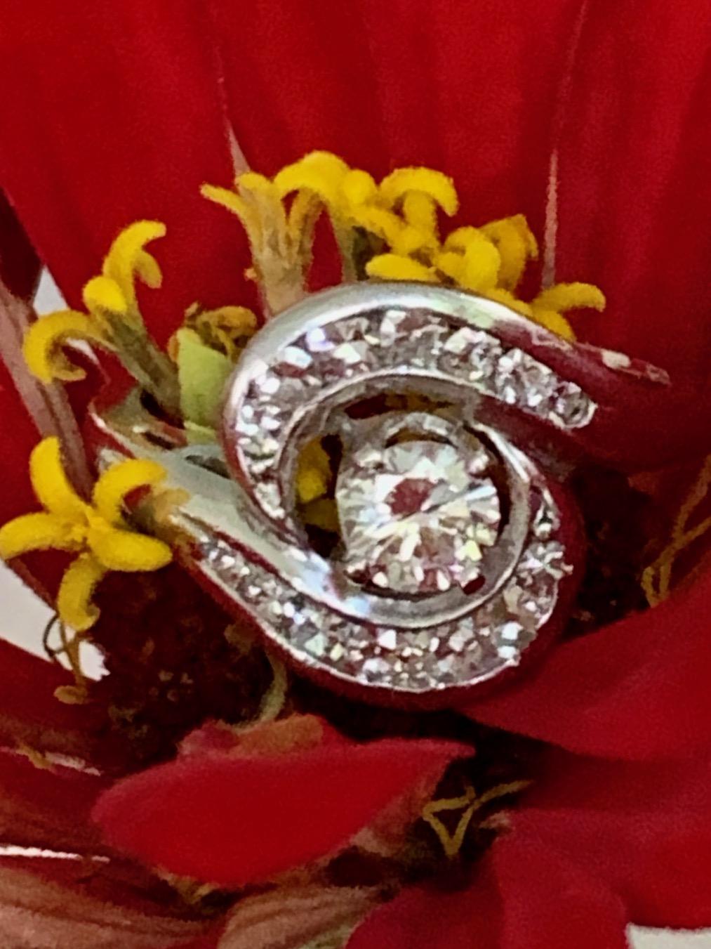 This modern 18 karat white gold Diamond ring features a center brilliant cut 4.5mm Diamond which is .35 carat.  It has an average grade of SI-G/H.

There are 14 single cut side diamonds which swirl around the center stone.  They are approximately