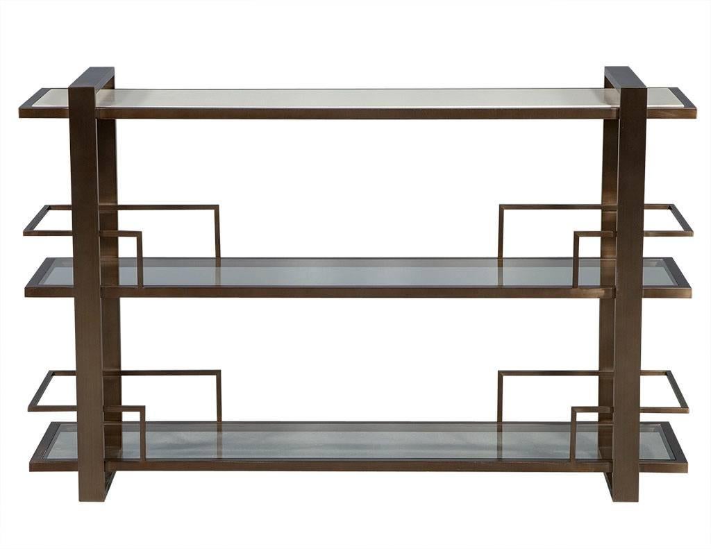 This modern drink console has Asian flair.  The piece has three levels, with the top boasting a grey speckle/beige marble inset in a brushed metal frame.  The lower two shelves are glass framed in metal, making this perfect for an entertainer and