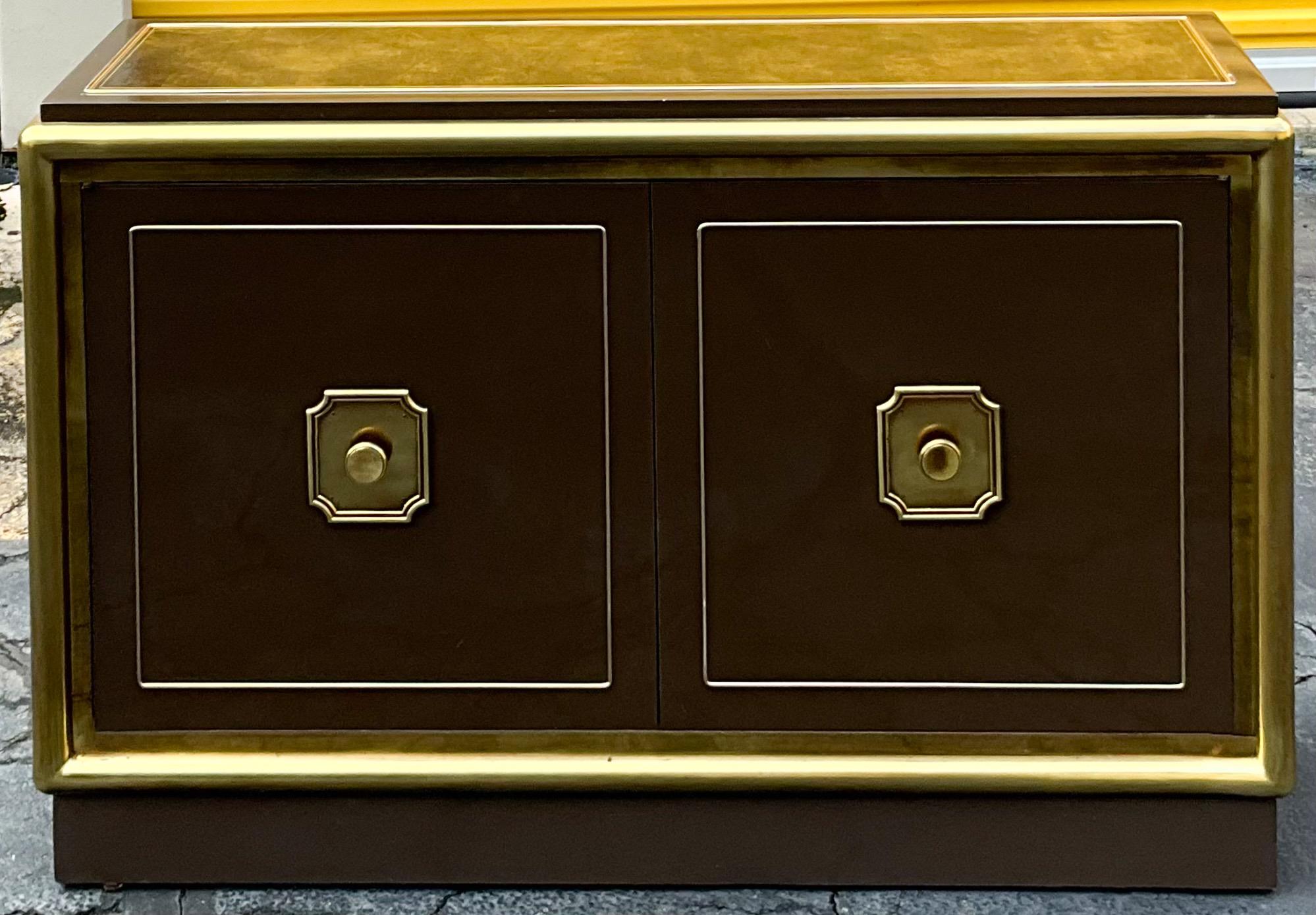 This is a unique piece by Mastercraft! I think it is post 1974 when they were purchased by Baker Furniture. It is a brown lacquer with tubular brass accents. The top appears to be a faux marbleized leather. It opens to an adjustable shelving. There
