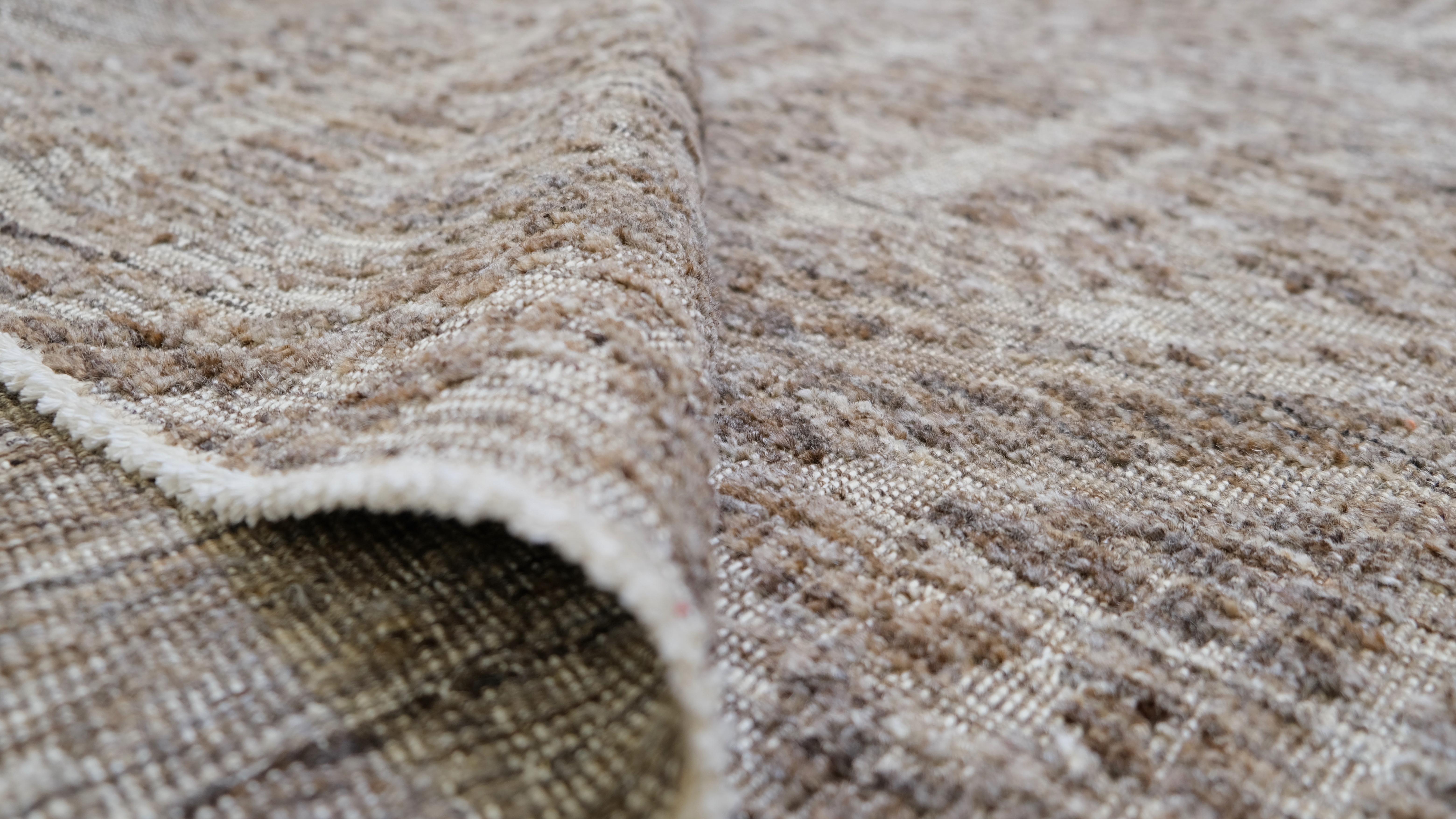 Elevate your living space with this exquisite hand-knotted wool rug, featuring a distinctive geometric tribal-inspired pattern in earthy tones. This rug showcases intricate detailing and a unique interplay of texture and design, making it a striking