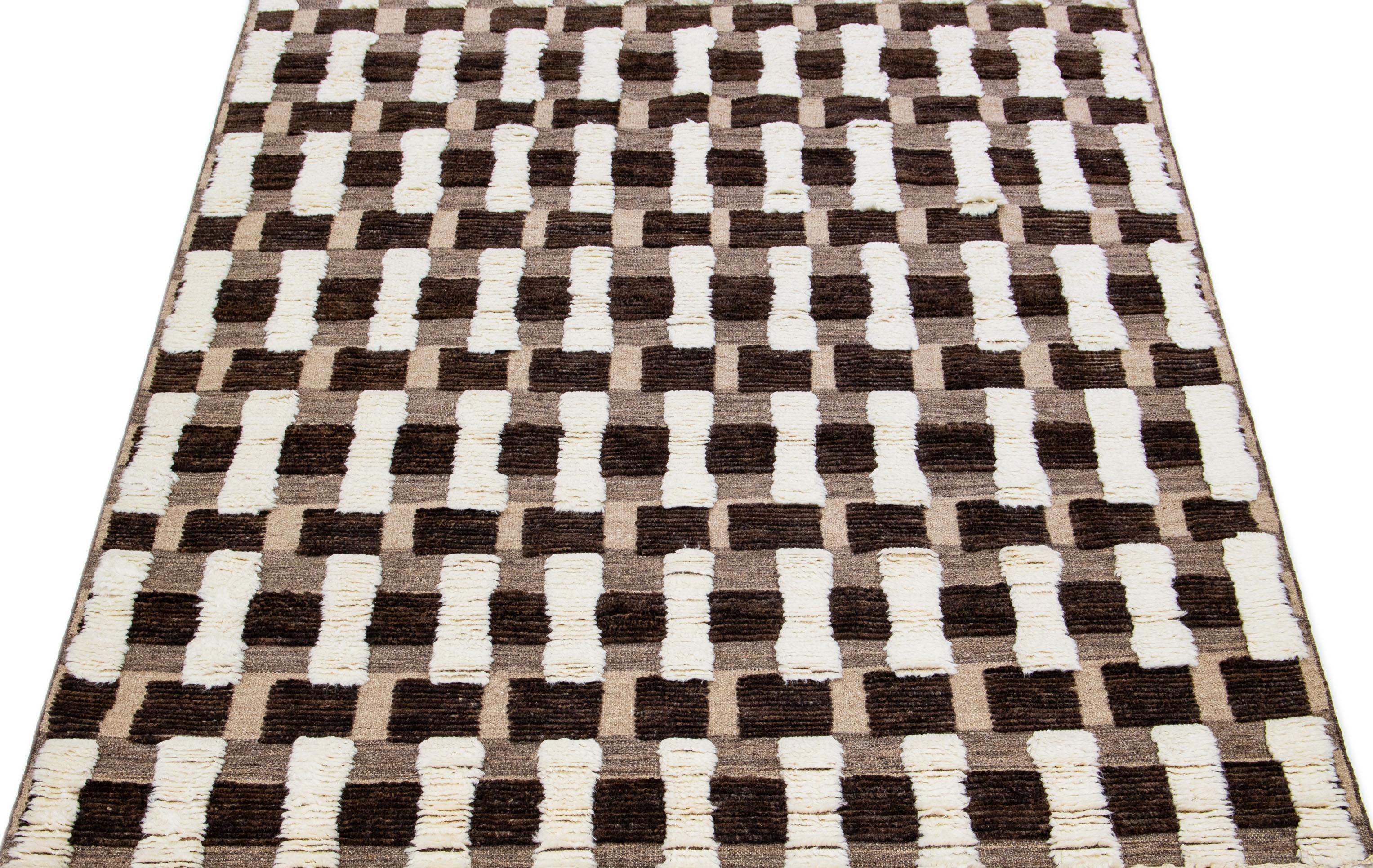 This handcrafted wool rug features a modern Moroccan design in a soothing Ivory hue, skillfully contrasted against a captivating brown backdrop. The harmonious blend of these colors forms a seamless abstract composition, leaving a remarkable and