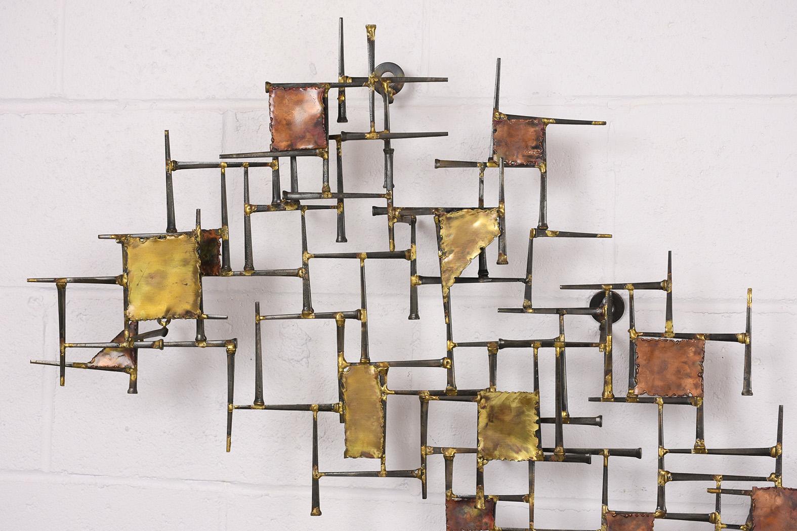 This is a 1960s midcentury Brutalist style brass, metal, wall sculpture features varying sized geometric shapes on a woven into a forged nail base. This sculpture is intriguing, sturdy, and ready to be hung on any wall for years to come.