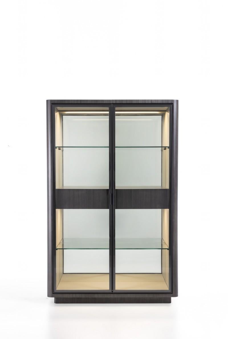 Showcase with an elegant linear design, the exterior structure embellished with dark Tay (VE50B) coating and rounded corner detail. The interior features fine details, dark Tay interior drawers, leather upholstered interior structure, mirrored