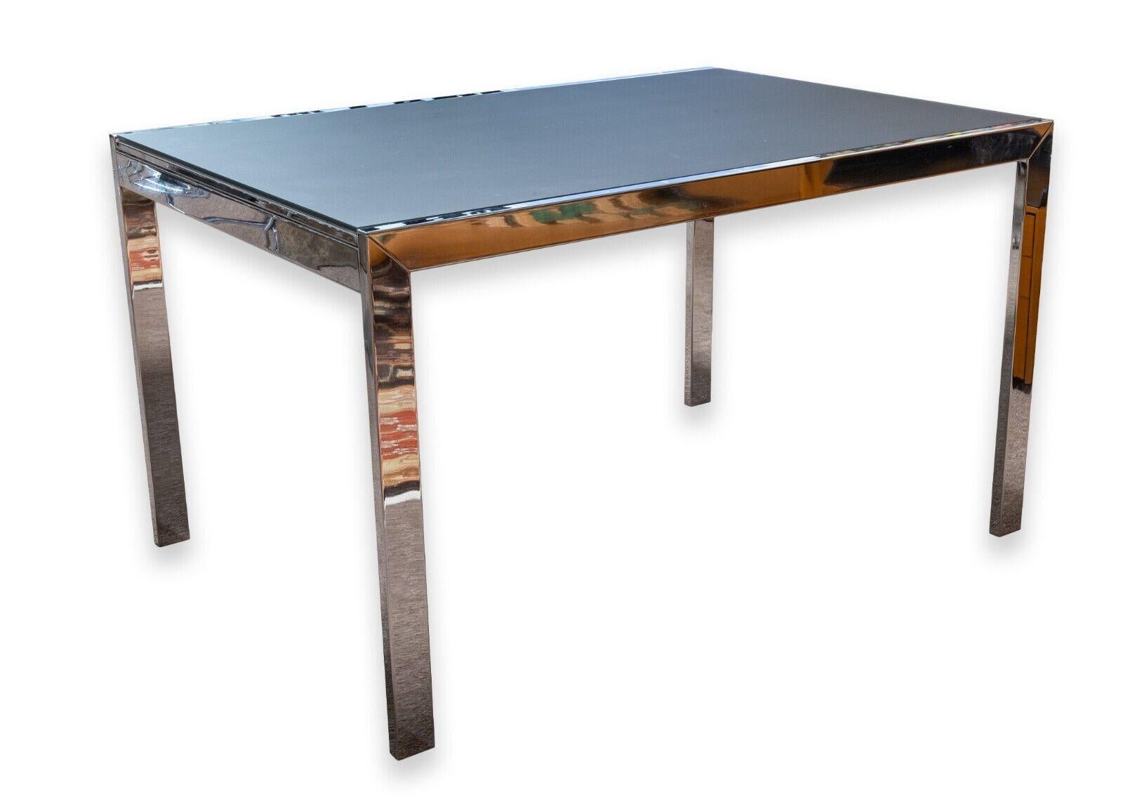 A Calligaris key expandable dining table. This is a stunning modern dining table featuring a metal chrome frame and a black smoked glass table top. This table features an expanding table top design, which is stored and pulls out from underneath the
