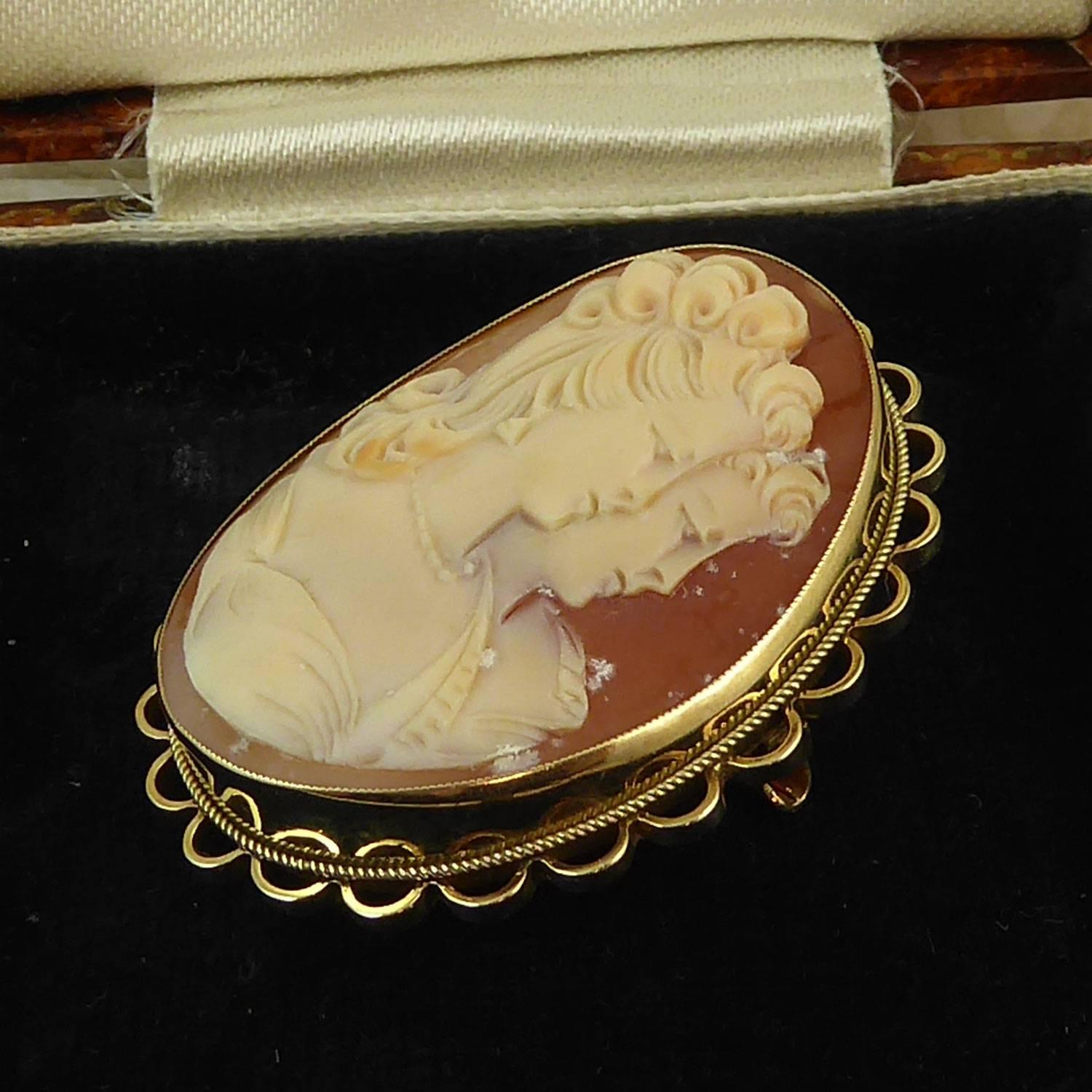 A recent vintage carved shell cameo depicting a classically carved young woman with reflection.  The cameo is very nicely carved with an elaborate hairstyle, jewellery and dress.  The cameo is mounted in a plain yellow gold band with a fine rope
