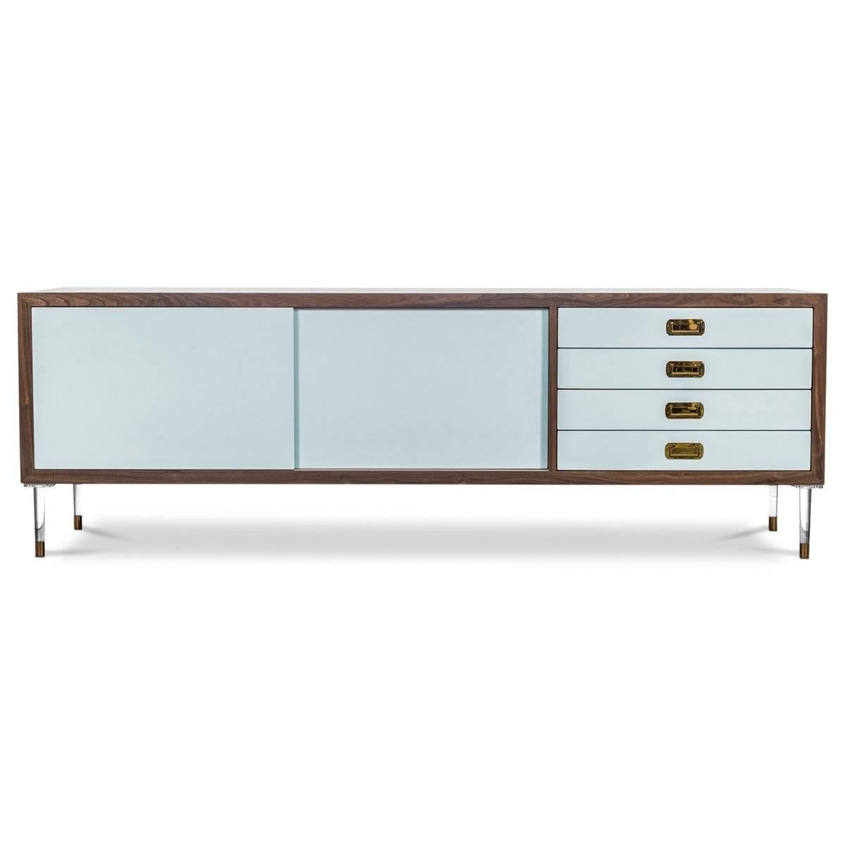 Introducing our new St. Martin Credenza featuring two sliding doors and four drawers to maximize its functionality while still being stylish and chic. This retro-modern design features an oiled walnut trim, brass hardware, our famous Capri Blue