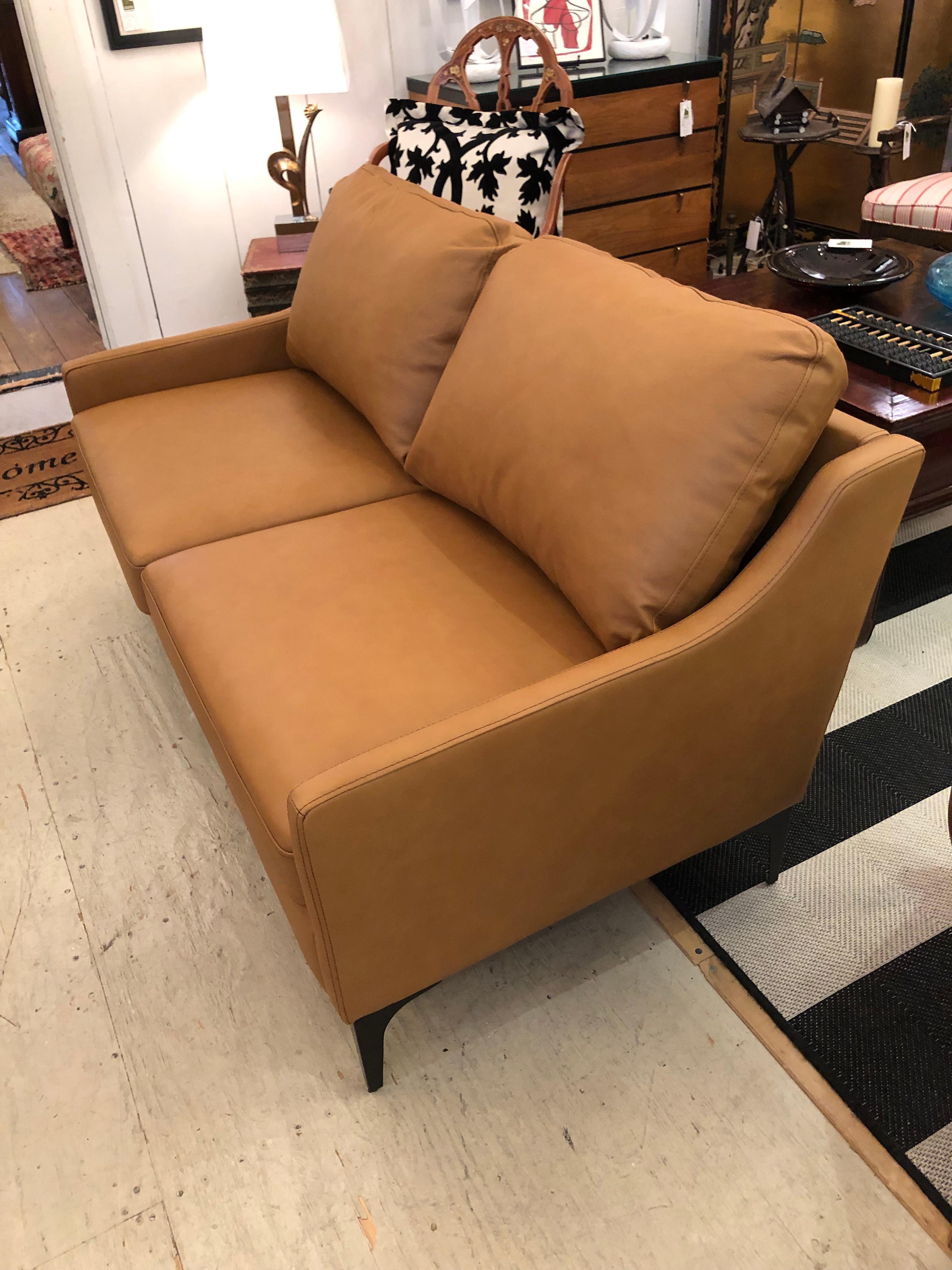 Supple and smooth contemporary leather sofa loveseat having caramel color and two removeable seat cushions as well as two back cushions. The seats cushions have velcro to keep them from slipping. Tailored mahogany legs complete the sleek