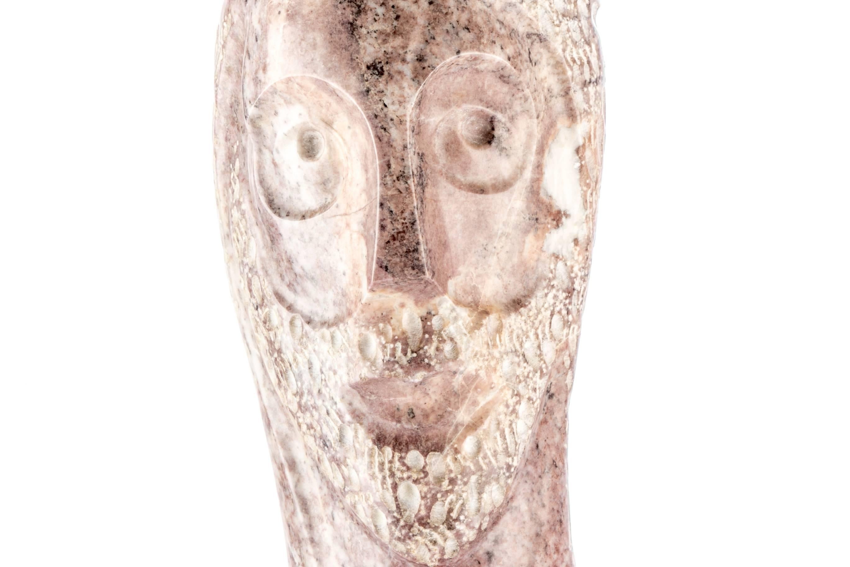 20th century modern carved marble sculpture depicting head, carved pink/purple and white marble tall thin stylized head of a bearded male with a helmet like top and deep eye sockets, mounted on a tiered mirrored metal base, signed 