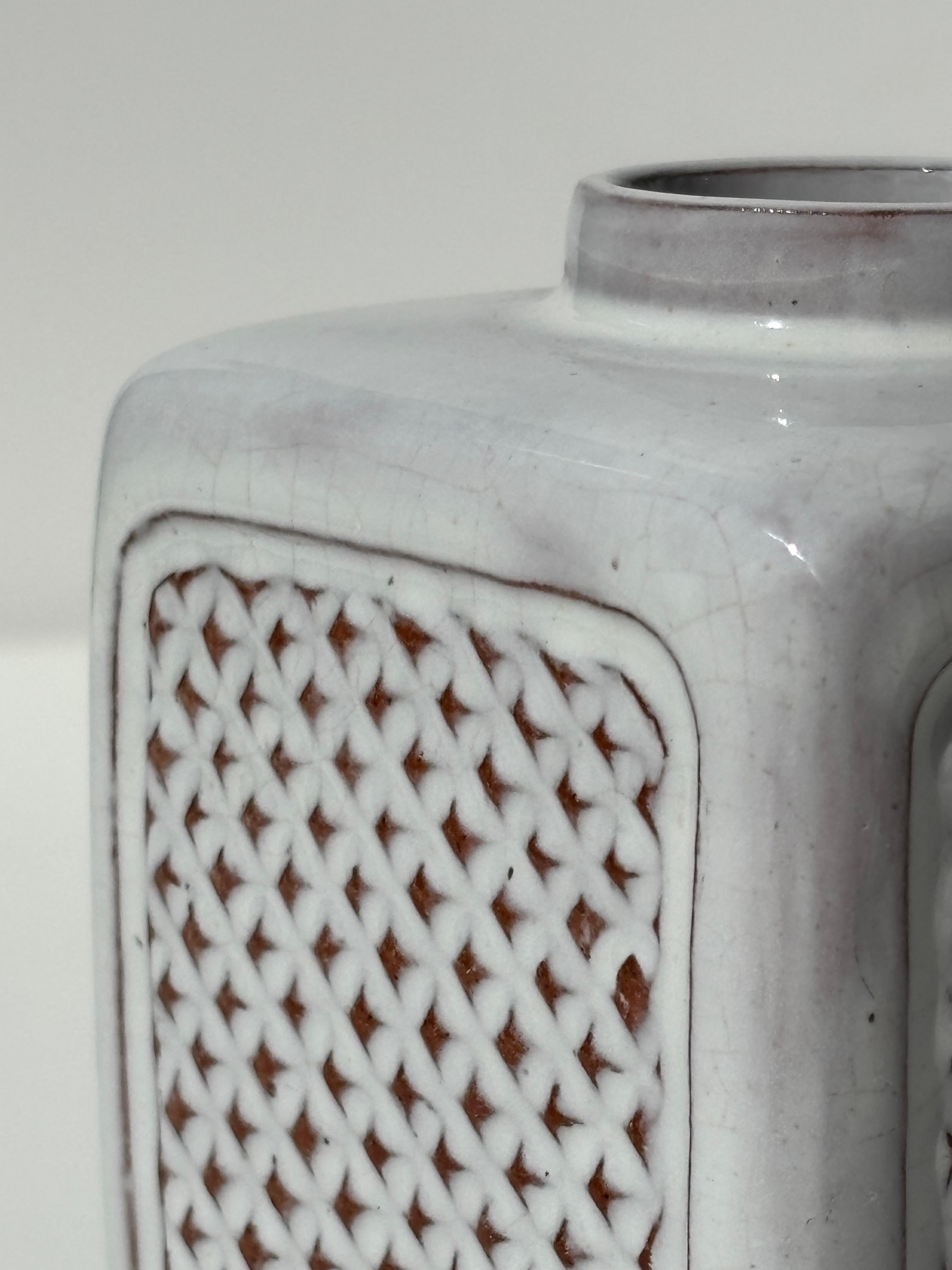 Vase moderniste gris clair conçu et produit par l'artiste céramiste et sculpteur danois Herne Nielsen (1912-1981) dans son atelier privé dans les années 1960. Décor géométrique en relief sur les quatre faces. Signé et numéroté sous la base. 
Belle