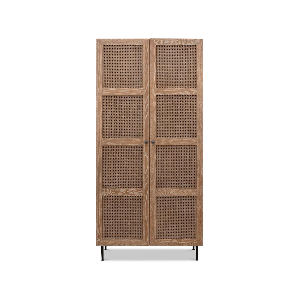 An elegant modern cabinet with two caned doors in a cerused white wash oak finish. The interior is fitted with shelves and raised on simple modern metal legs.

Dimensions: 35