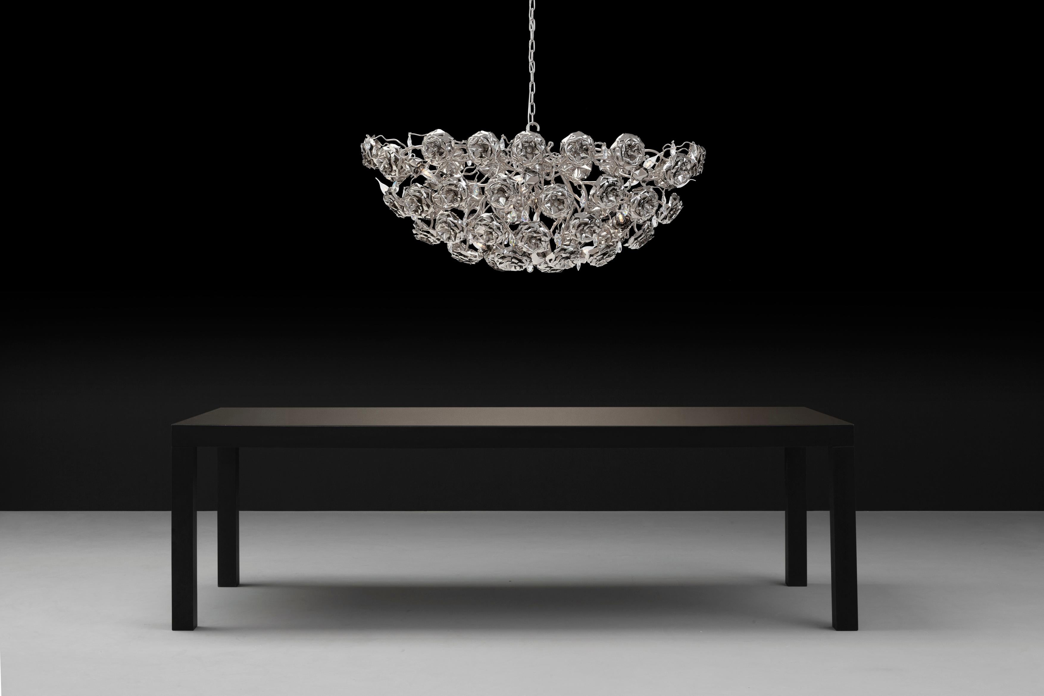 This modern chandelier in an oval shape and nickel finish is part of the Love You Love You Not collection, designed by William Brand, founder of Brand van Egmond. Evocative and eyecatching, between the handcrafted roses, sparkling crystals have been
