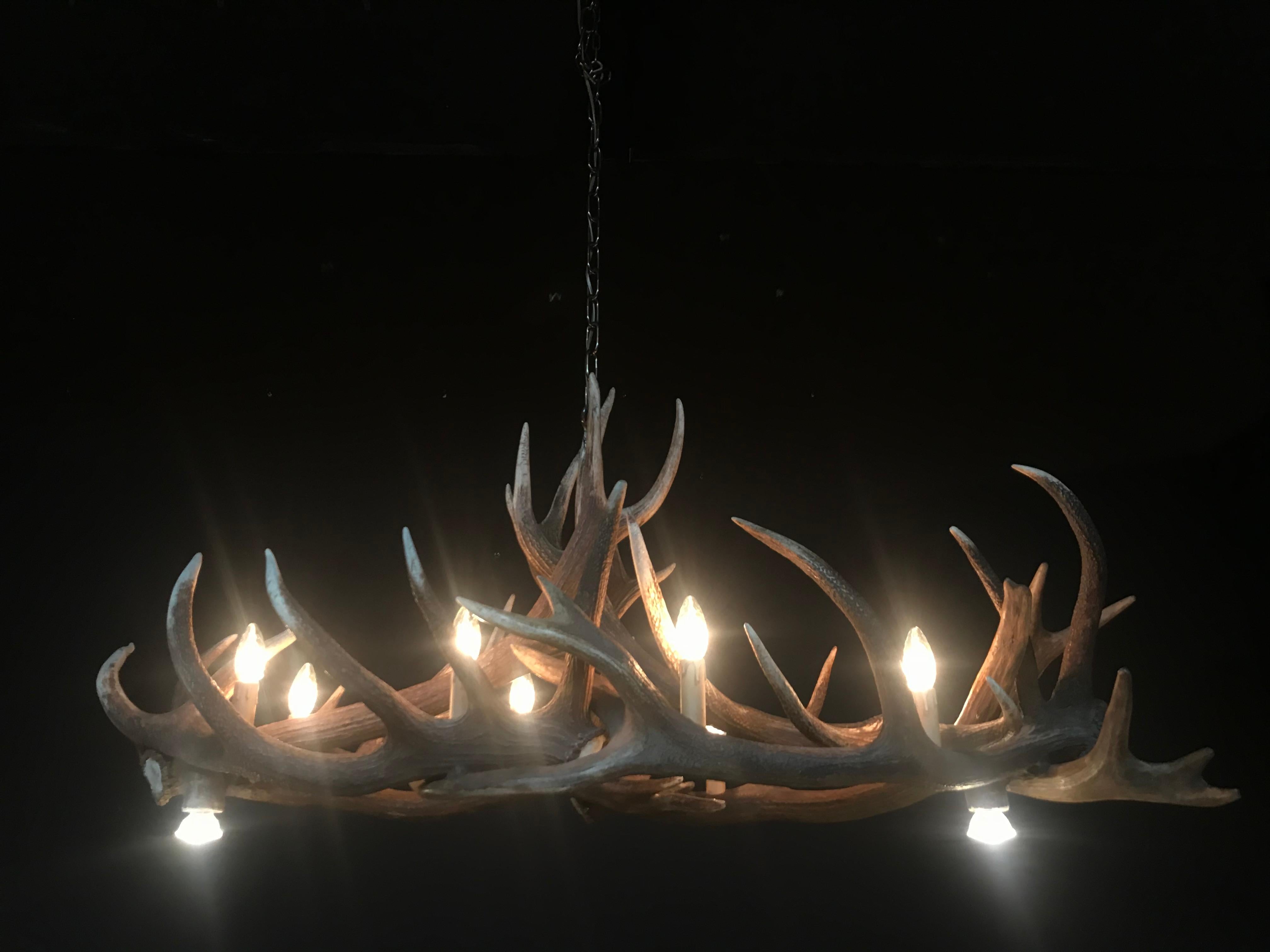 Modern chandelier made of antlers (HG 104). The chandelier is made of red stag antler. The 2 spots on the bottom can be switched on and off with a switch.
The electrical wiring is concealed in the antlers and the quality of our chandeliers is