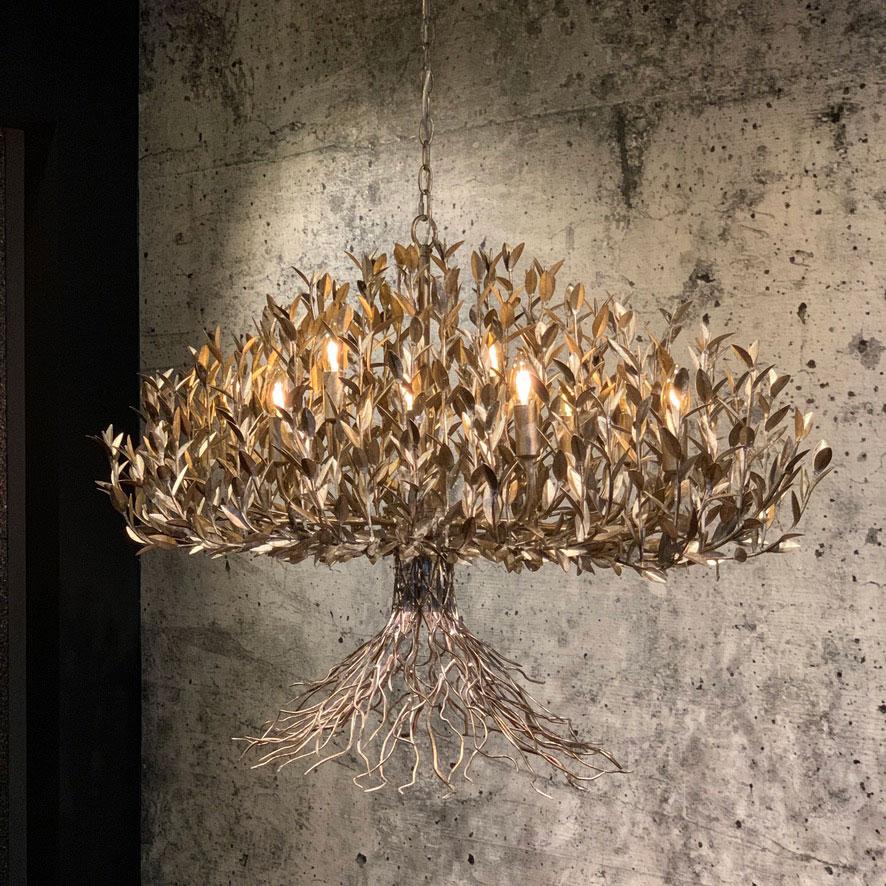 Modern chandelier made of metal and shaped into the model of a tree. 
This lamp features 12 lighting points in between the leaves and a spot underneath for extra light on your table.

The lamp is available in three different colors: