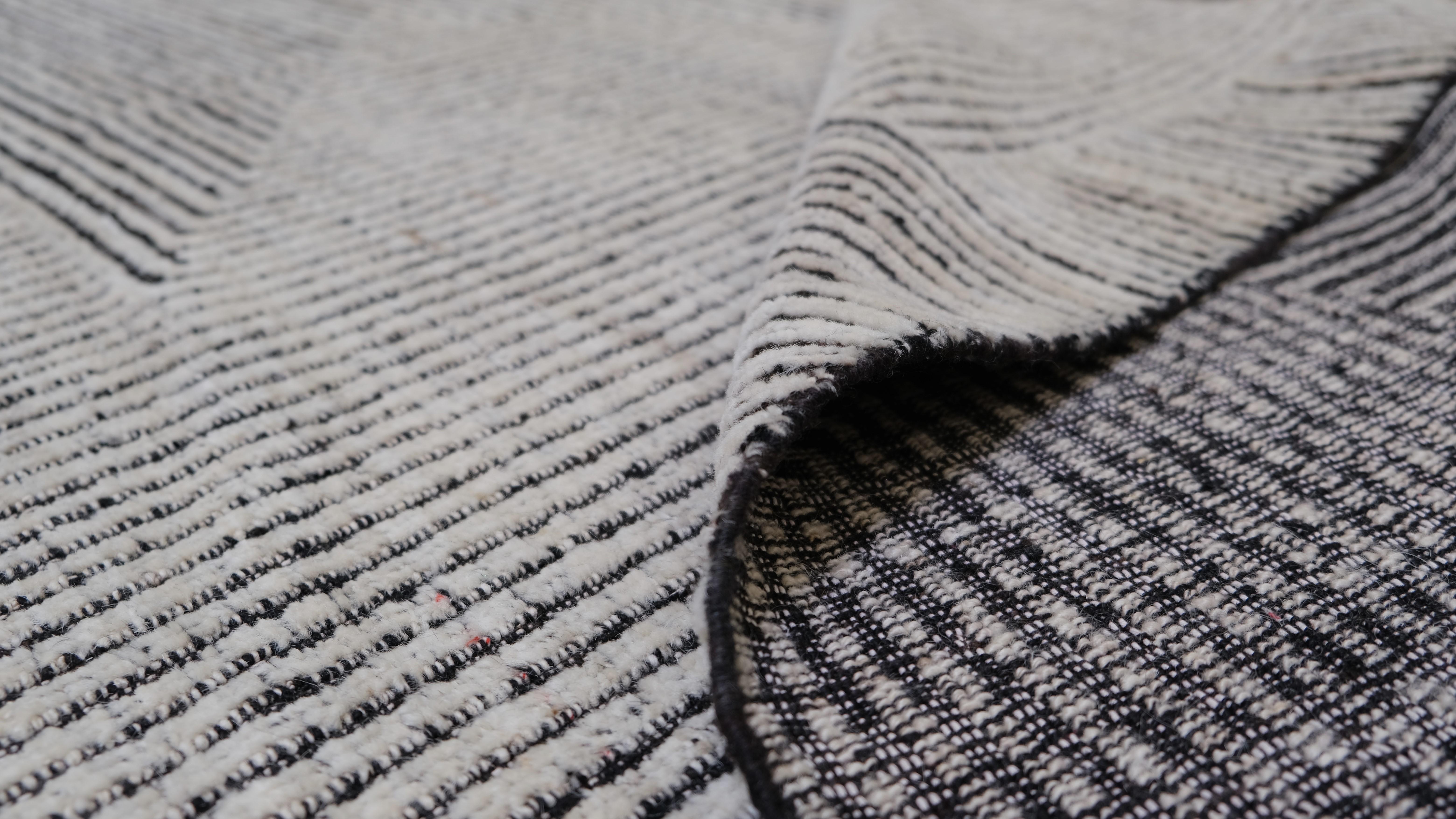 Dieser moderne, handgeknüpfte Wollteppich zeigt ein elegantes, lineares, geometrisches Design in Anthrazit und Elfenbein, das eine auffallende, minimalistische Ästhetik bietet. Die sorgfältig angeordneten Linien und kantigen Formen schaffen ein