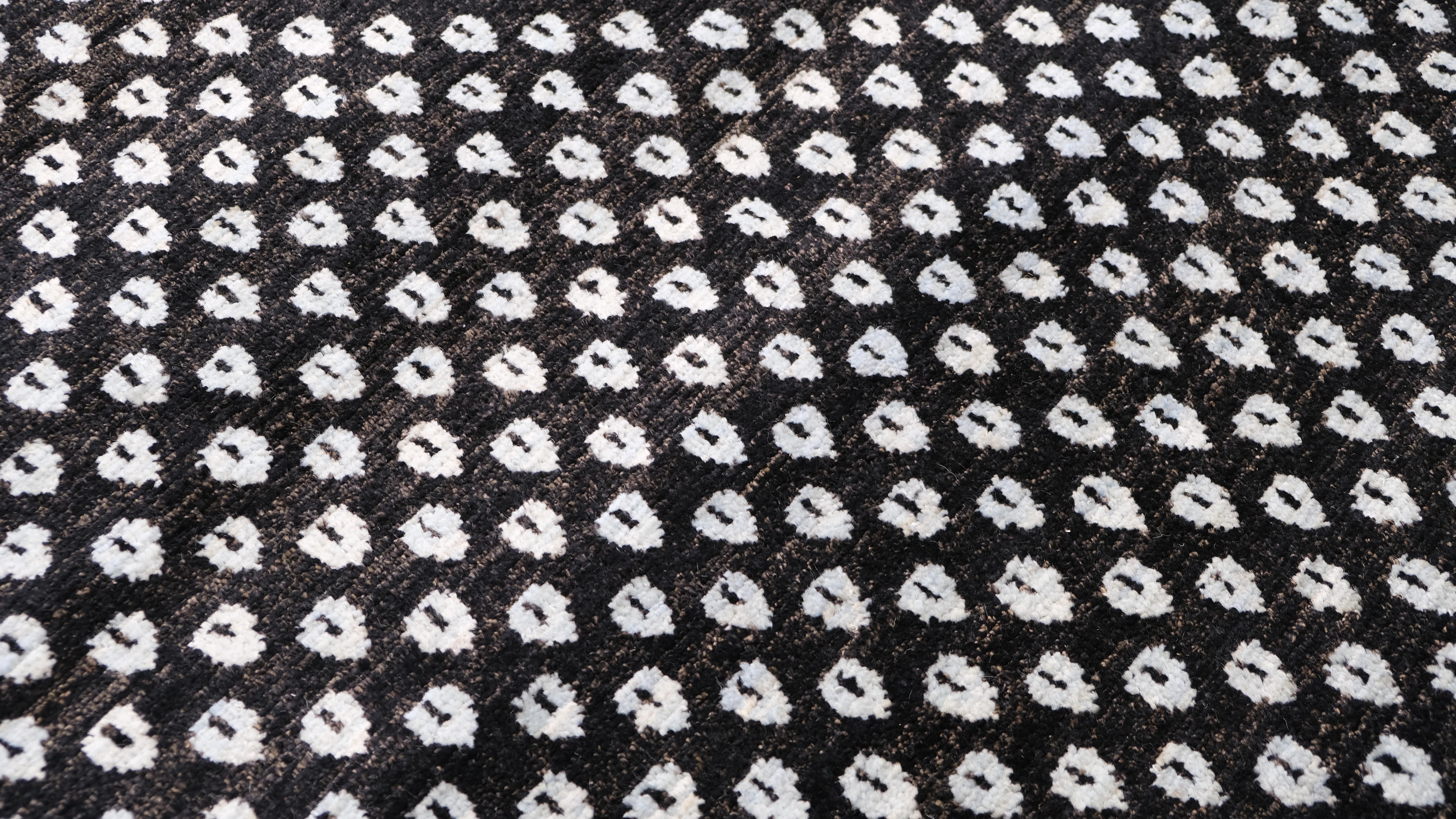 Questo tappeto in lana annodato a mano è un'accattivante fusione di estetica moderna e artigianato tradizionale. Caratterizzato da un sorprendente motivo geometrico color antracite e azzurro, il tappeto crea una texture visivamente dinamica che