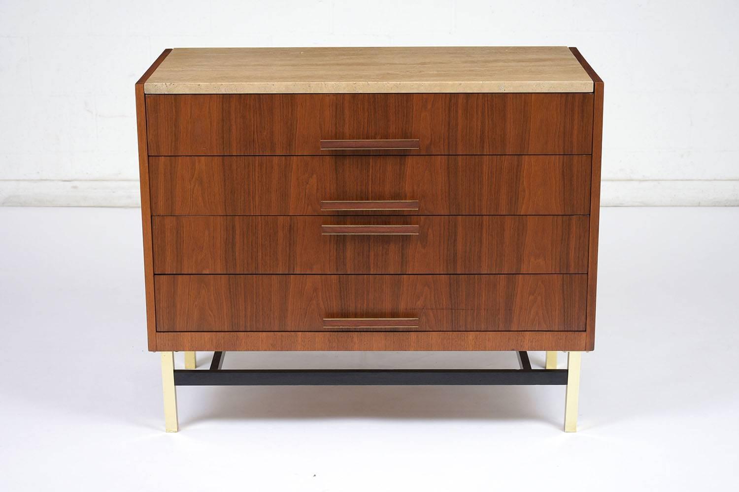 This 1960s chest of drawers is made by Heritage in the style of Paul McCobb. There are four drawers for ample storage with wood and brass drawer pulls. The walnut stained chest has a travertine slab insert on top. The brass legs are made sturdy by