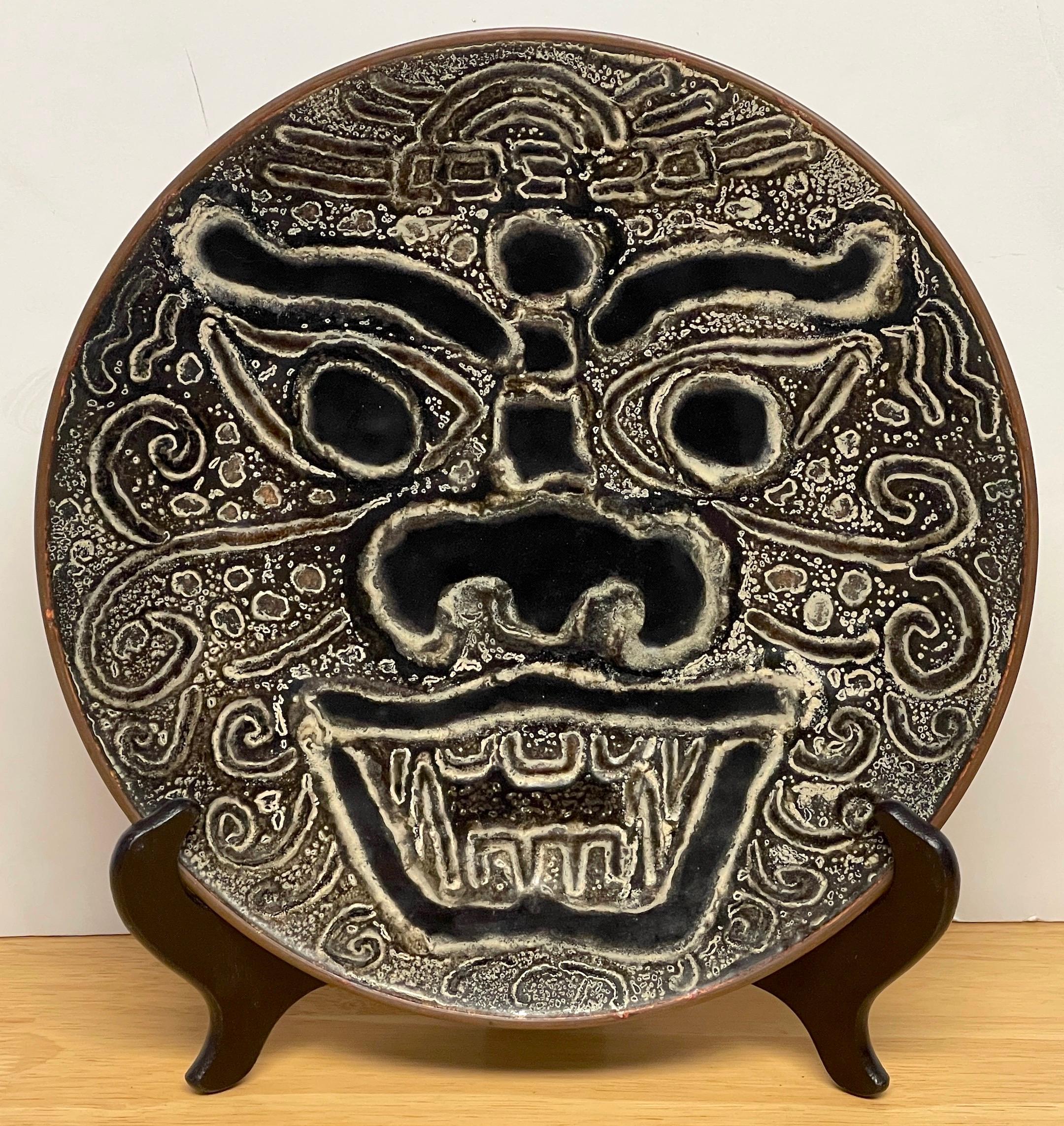 Modern Chinese Export enamel foo dog motif charger with stand 
The profusely enameled portrait plaque of a foo dog, with a Chinese hardwood easel stand. Unmarked.
The charger alone has a 10.5-Inch diameter, displayed on the stand the work stands