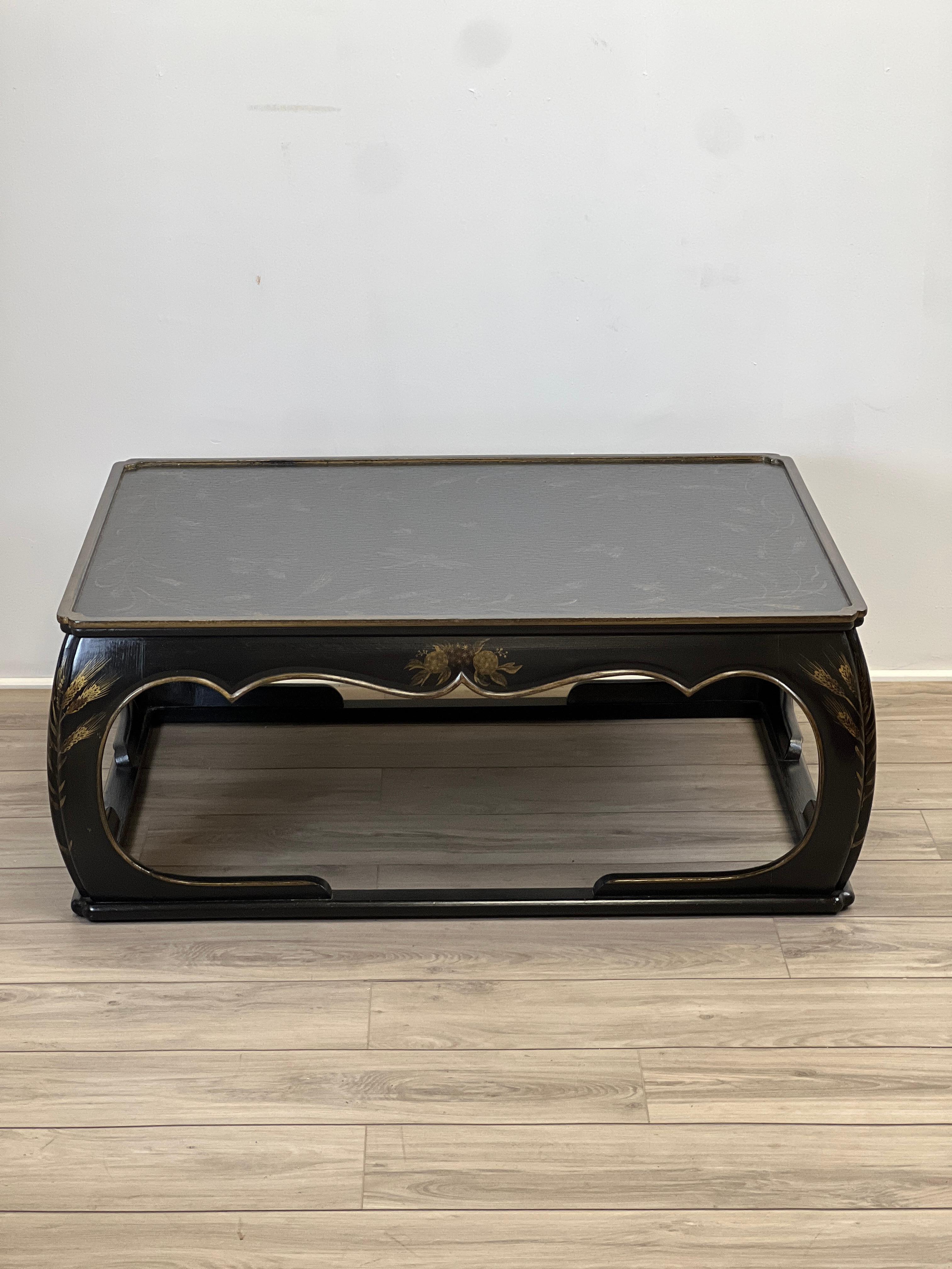 Featured is a well made black lacquered Chinoiserie style cocktail table. The item is hand-painted with gilt accents of a garden pond scene of butterfly's, dragon fly's, bees, grasshoppers, sparrows and what stalks. This is a solid and handsome