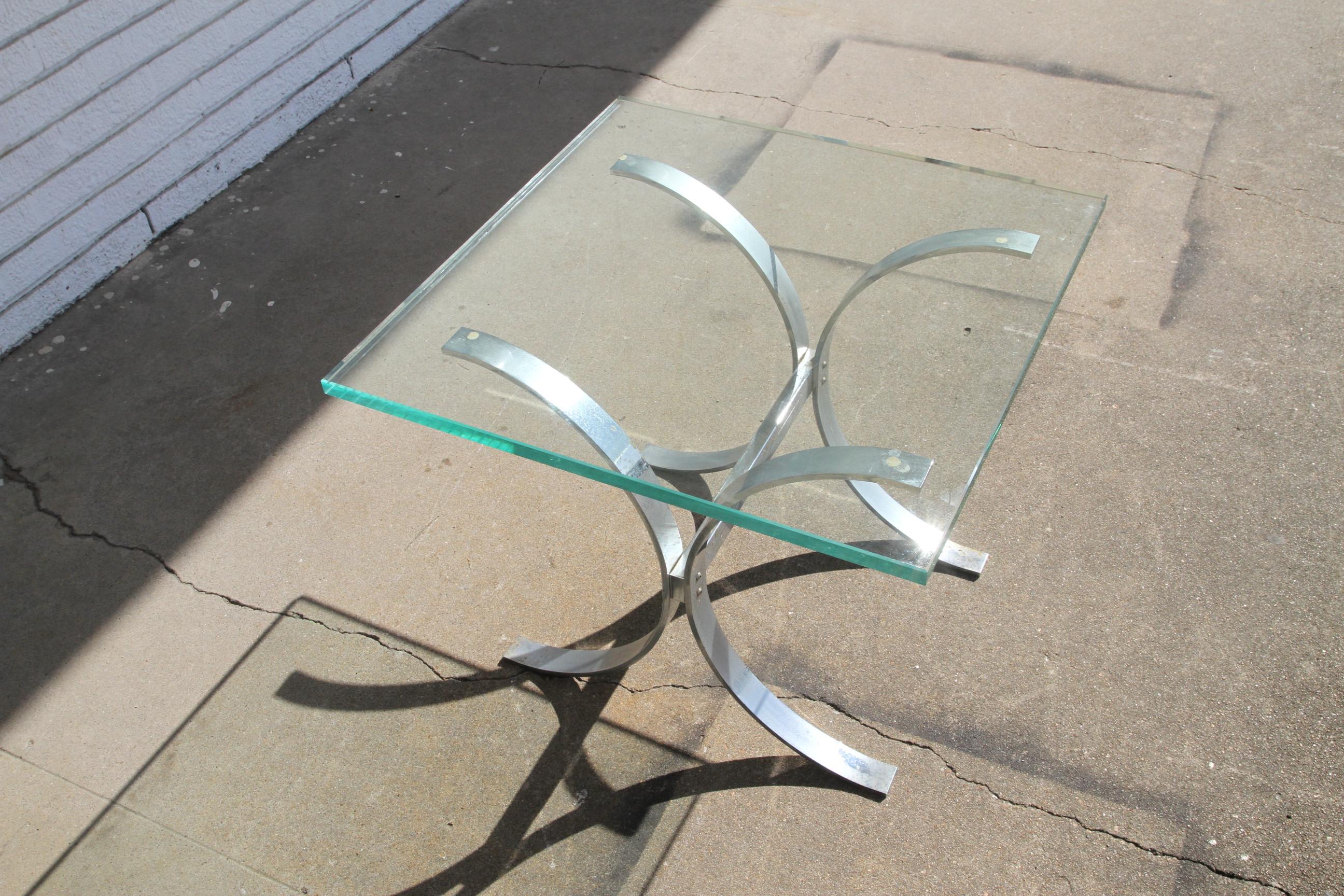 This is a sculptural table with a chrome base and a glass top. It's attributed to Ronald Schmitt. It's sleek design will fit nicely into any dwelling.  