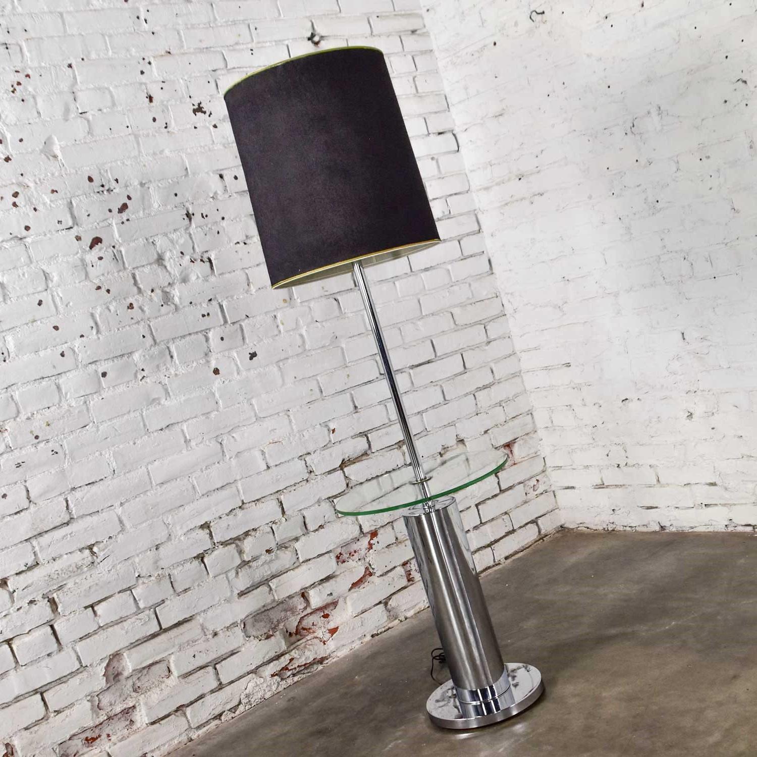 Fabulous modern chrome cylinder floor lamp in the style of George Kovacs. Comprised of a round chrome base, wide cylinder column, floating circular glass center shelf with a narrower chrome tube up to the socket base, and an optional lamp shade.