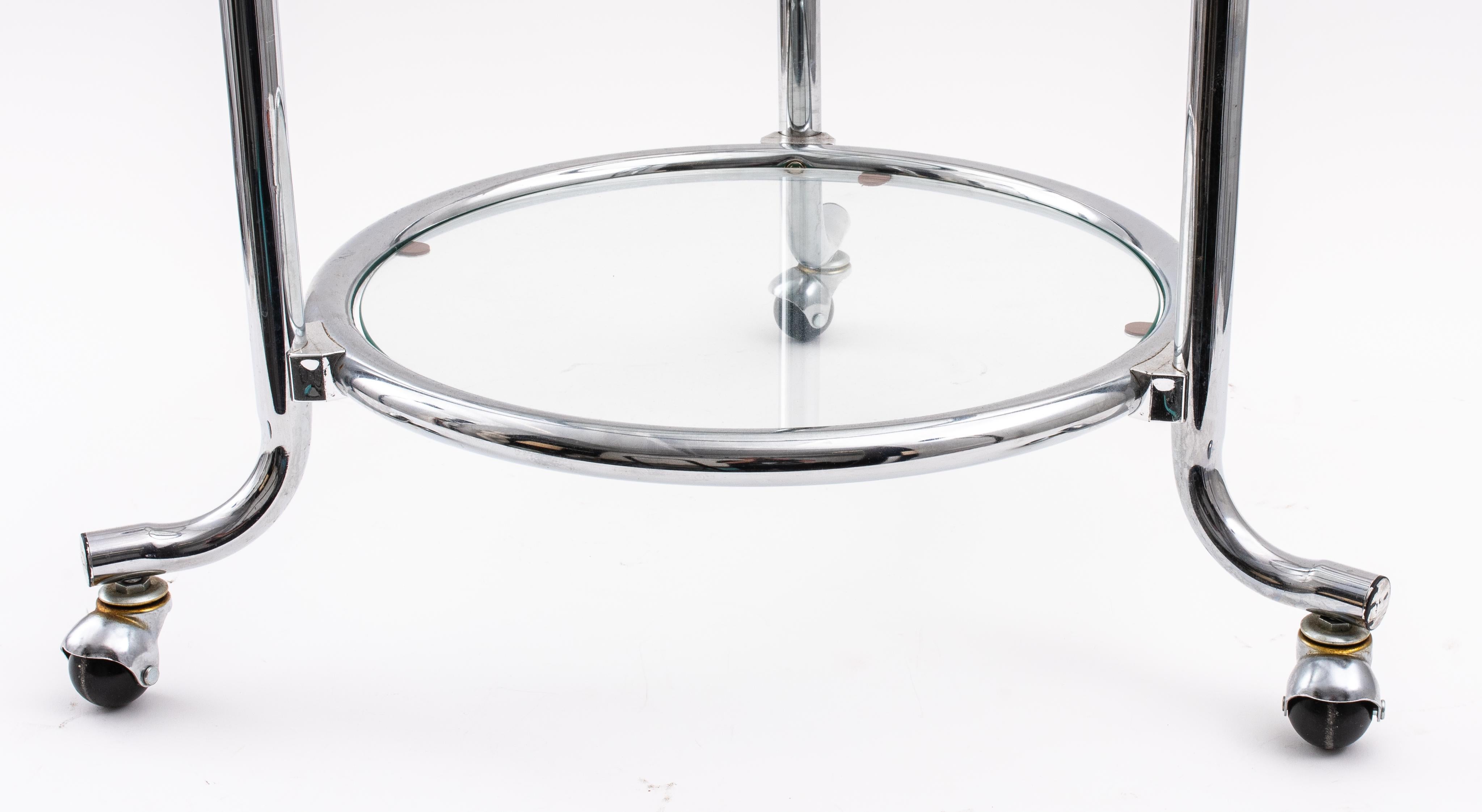 Modern chromed metal side table with three tiers of glass tops and on three wheels, apparently unmarked. Measures: 27