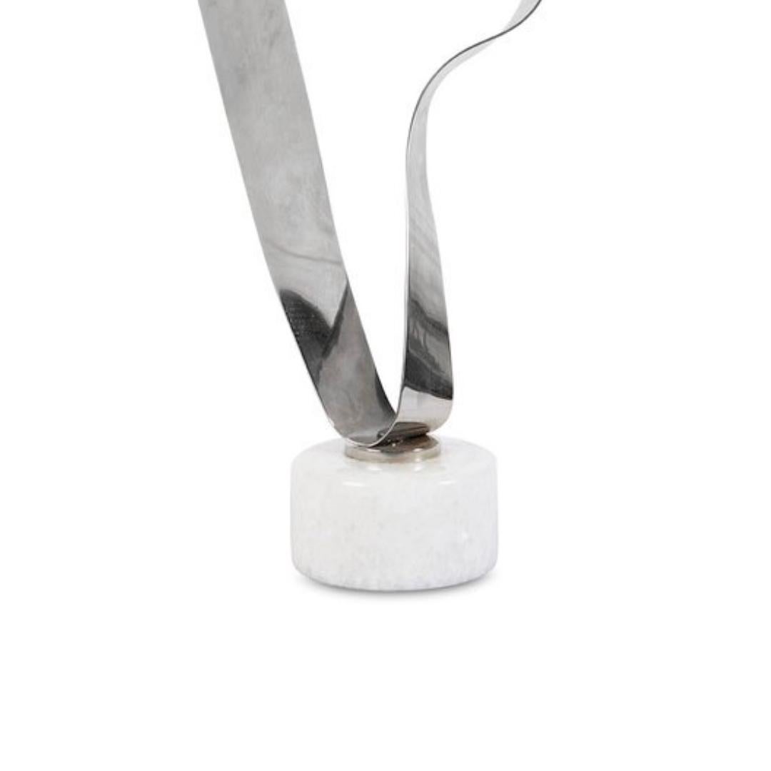 Diese moderne Skulptur aus Vintage-Stahl fängt die subtile Schönheit eines fließenden Bandes ein. Die auf einem weißen Marmorsockel montierte und glänzend verchromte Skulptur besticht durch ihre Eleganz und ihre sorgfältig vereinfachte Form. Die