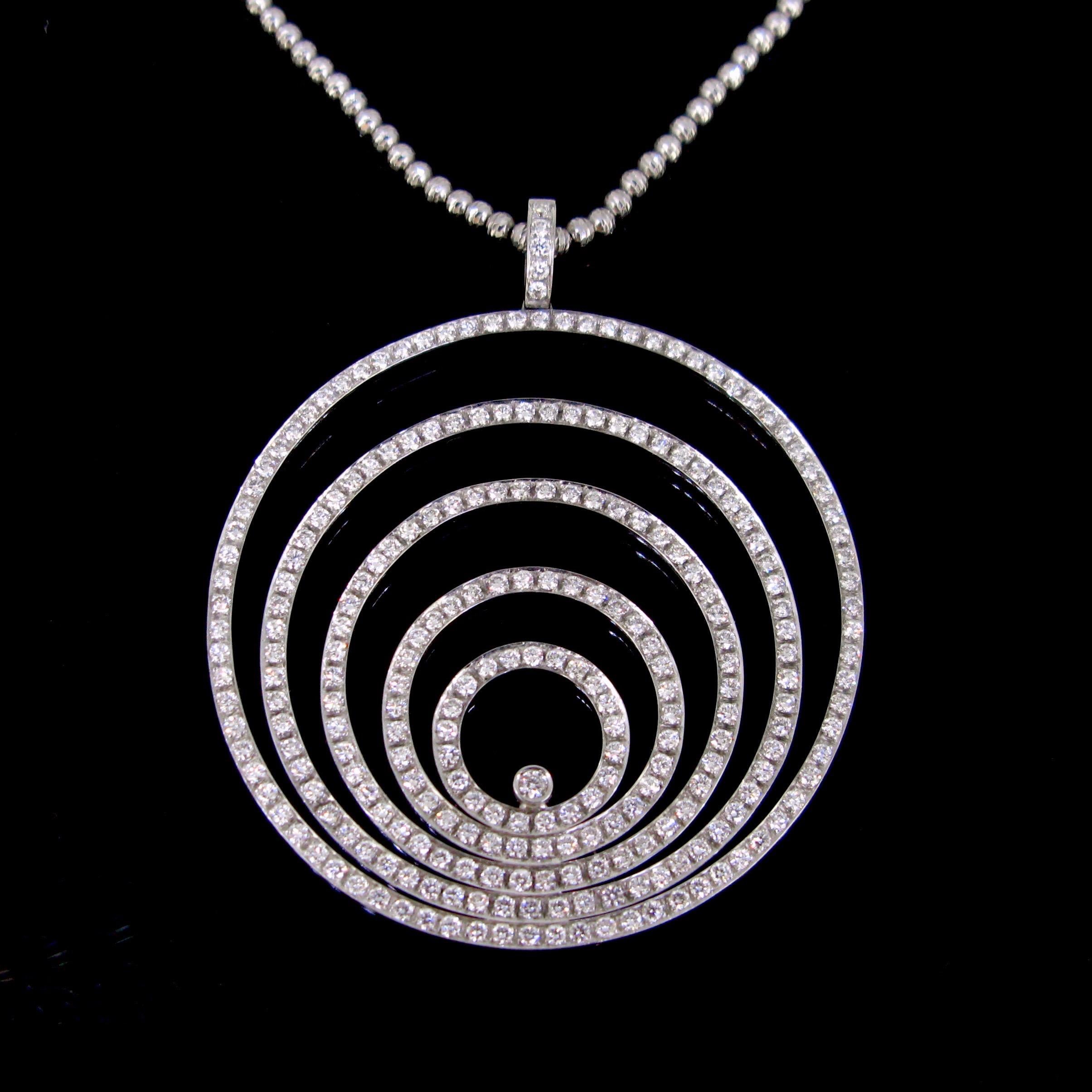 This modern and ravishing pendant comprises 5 ascending circles, all adorned with brilliant cut diamonds. It comes with a very nice 18kt white gold chain, with facetted gold beads. The chain is 40cm long. The pendant and the chain are controlled