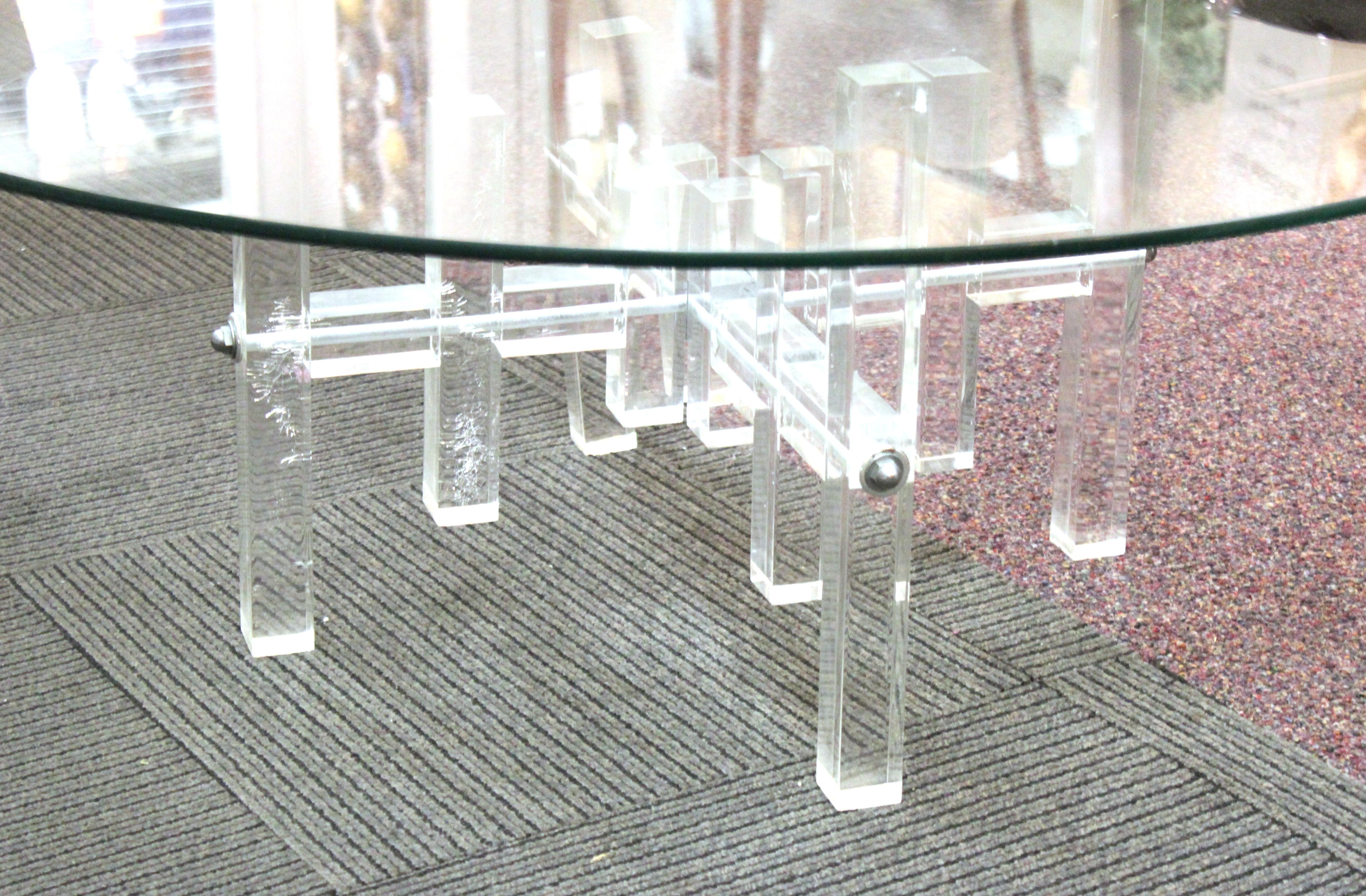 Modern coffee or cocktail table with a round glass top and a base made of assembled geometric Lucite elements. The piece dates from the 1970s and has age-appropriate scratches and some inner hairlines to some of the Lucite elements.