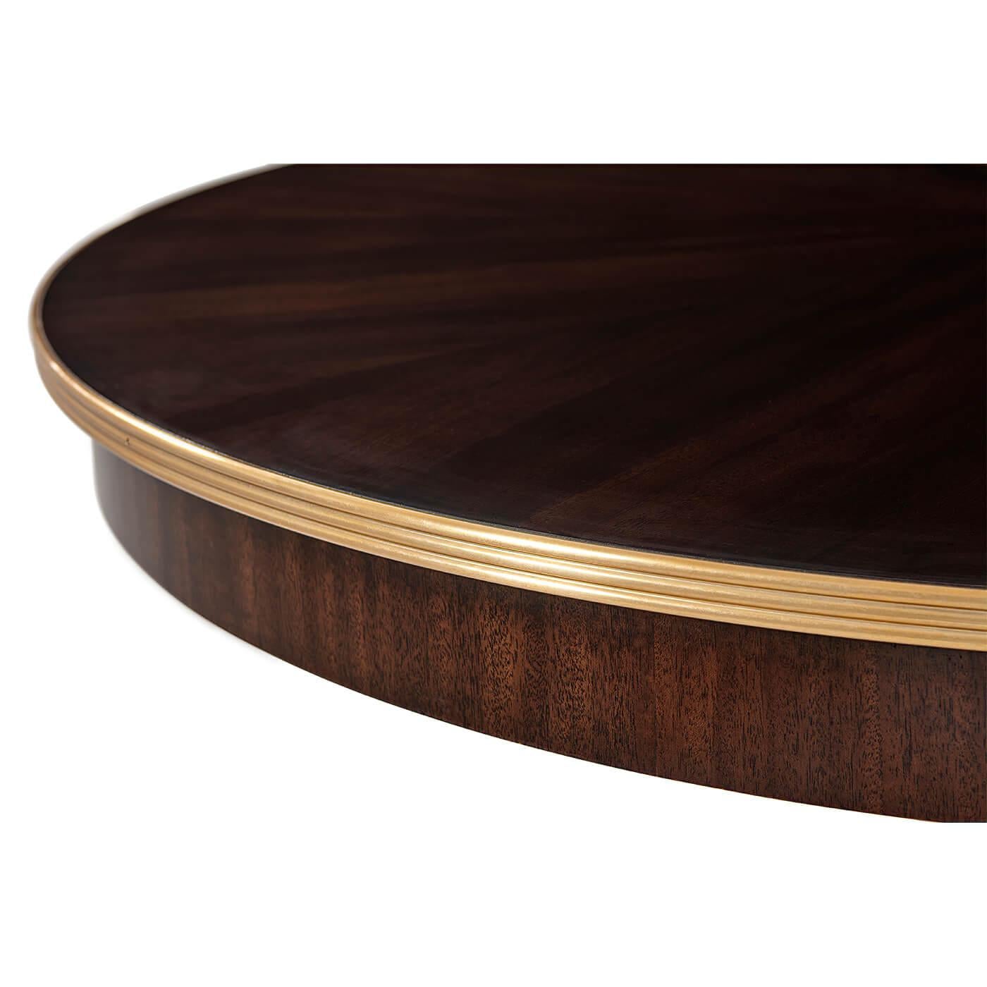 Modern Classic center table. The perfect petit dining room table or essential entryway table - the choice is yours. The round sunburst tabletop is figured in Mahogany veneer with a reeded edge outlined in brass. The down-swept monolithic table