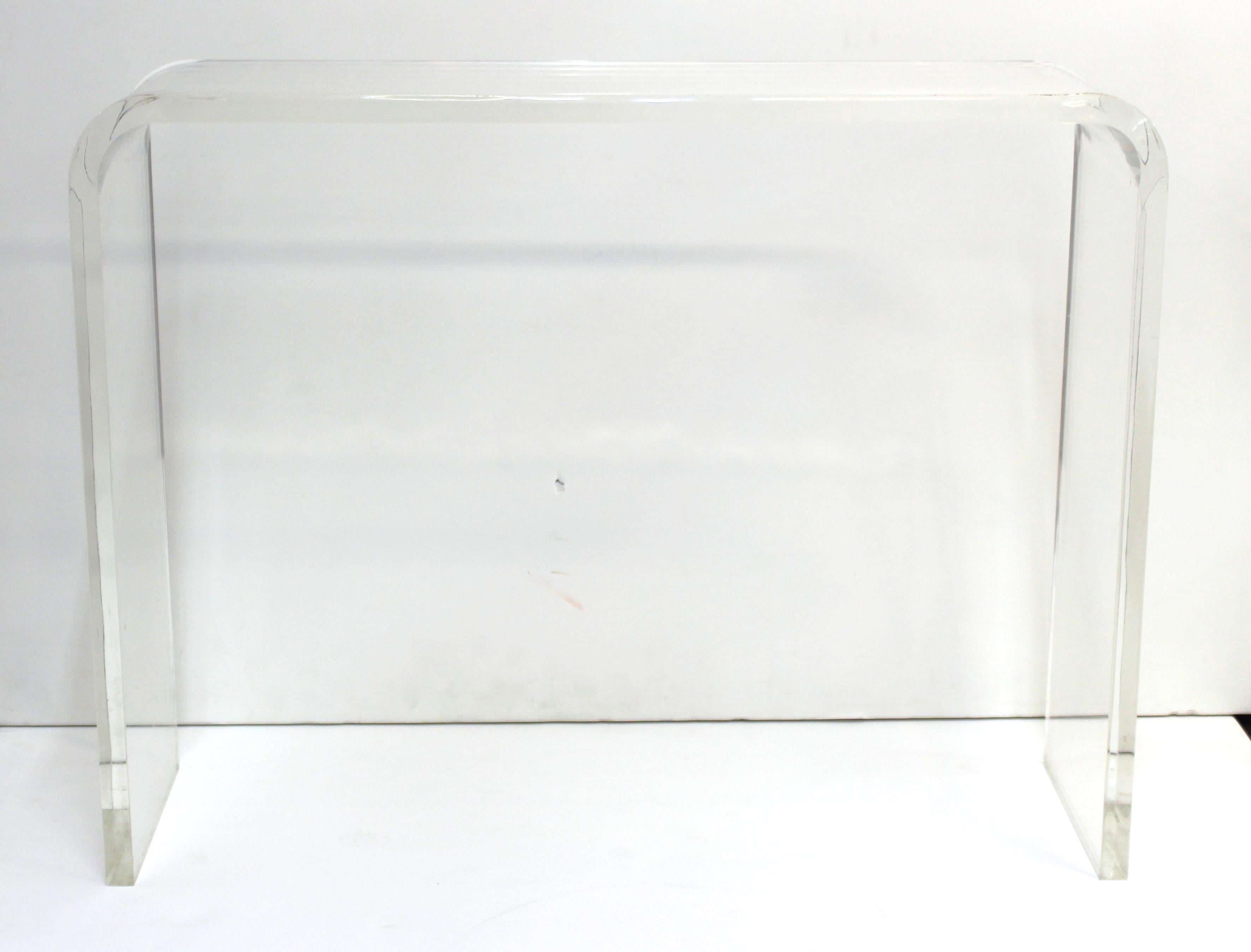 Modern waterfall console table made of clear and thick Lucite. The piece was likely made during the 1970s and is in great vintage condition with age-appropriate wear.