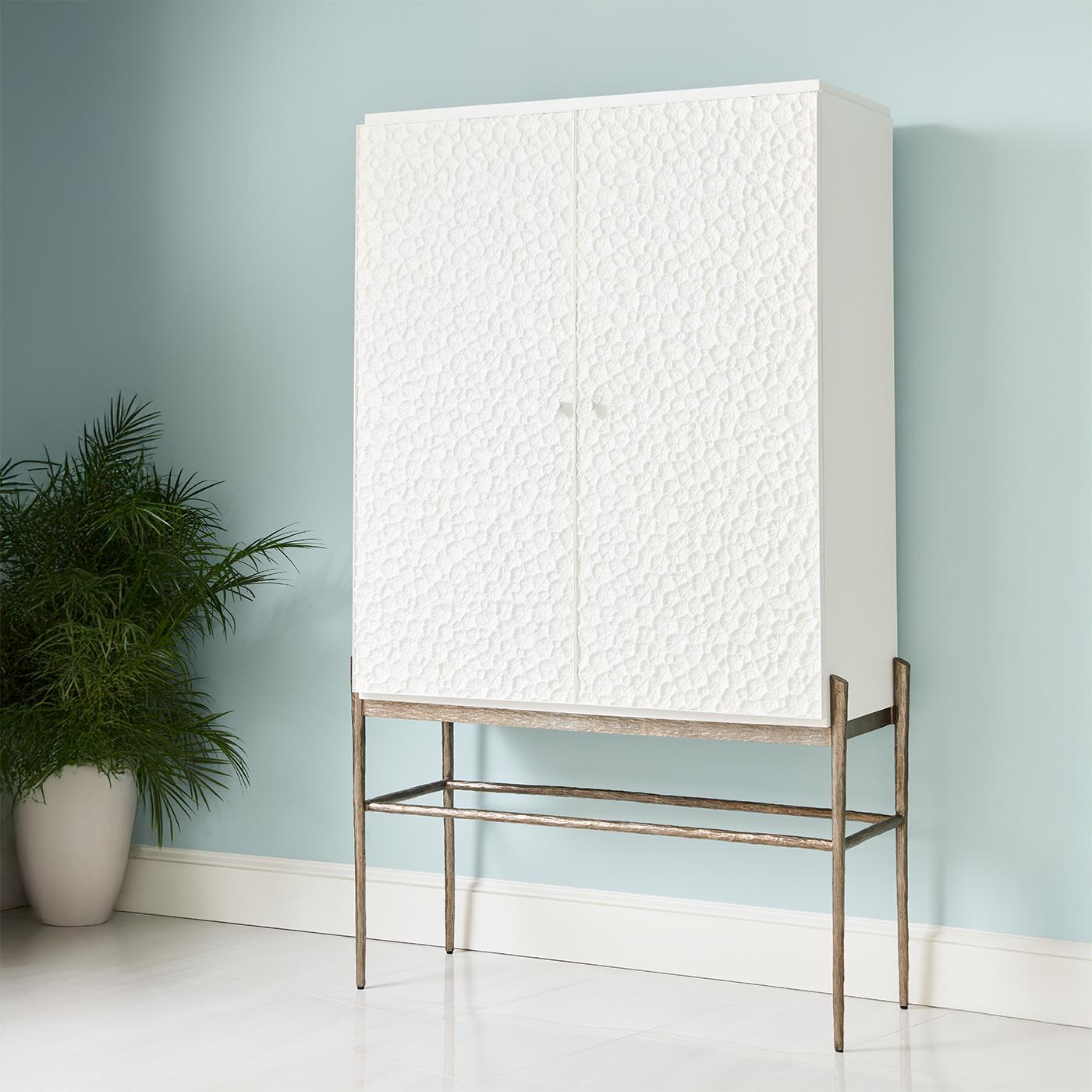 Inspired by fossilized coral, its intricately cast metal doors create a mesmerizing texture, while the bleached oak case exudes contemporary elegance. 

The cabinet stands gracefully on dramatically tapered cast metal natural form legs. Inside, a