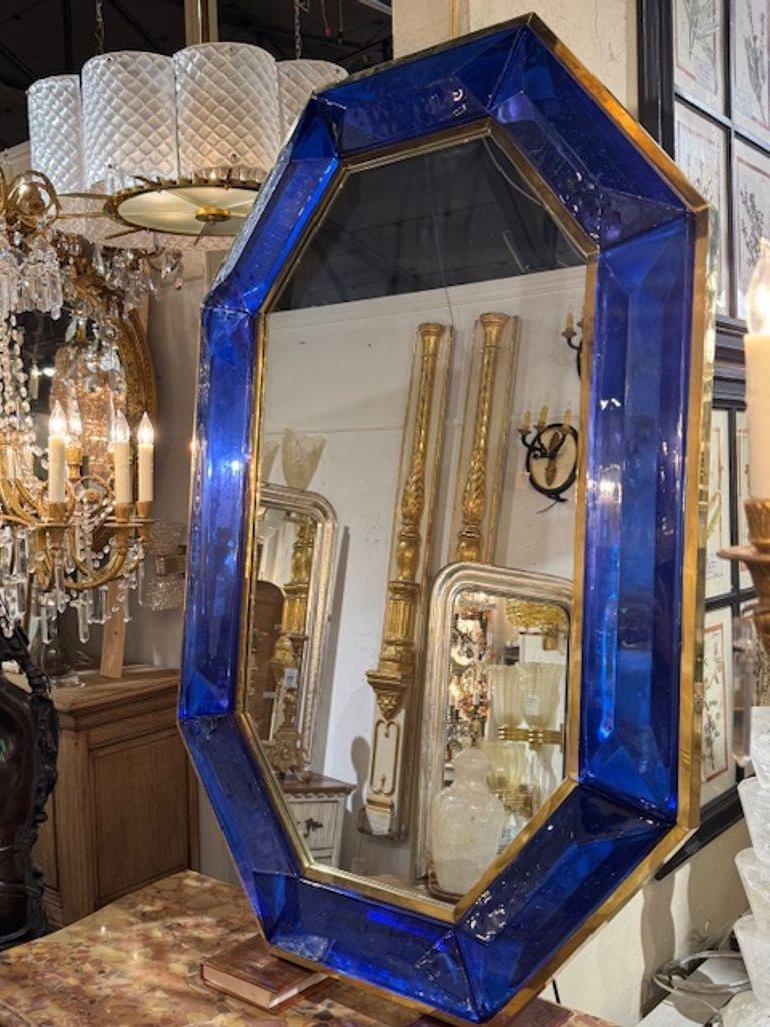 El producto es un moderno espejo octogonal de cristal de Murano azul cobalto con detalles de latón. El cristal reluciente añade un verdadero toque de elegancia a cualquier habitación. Su vibrante color azul cobalto y su exclusivo diseño octogonal la
