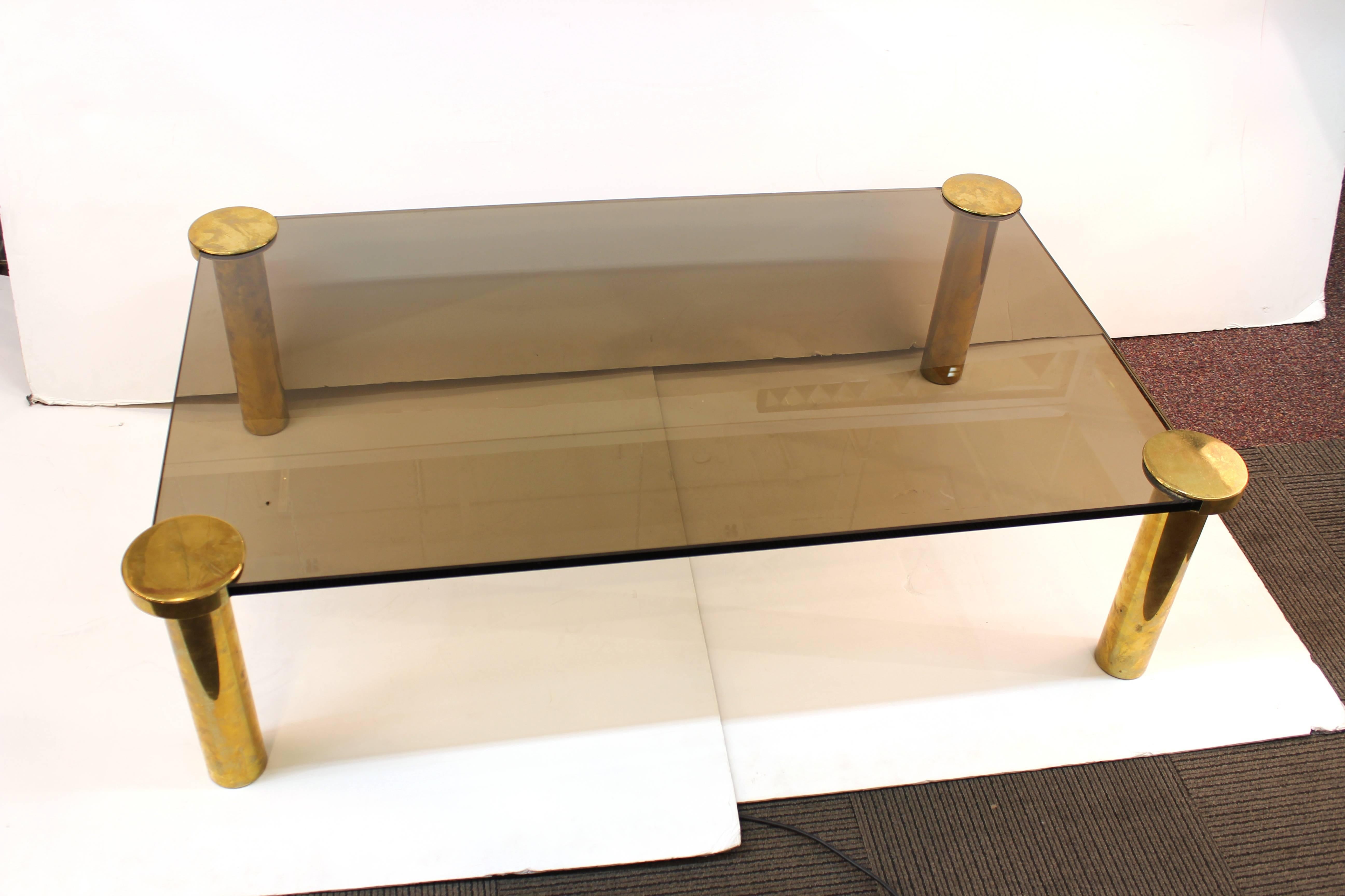 A modern cocktail or coffee table with glass top and tubular brass legs. The piece is in good vintage condition.