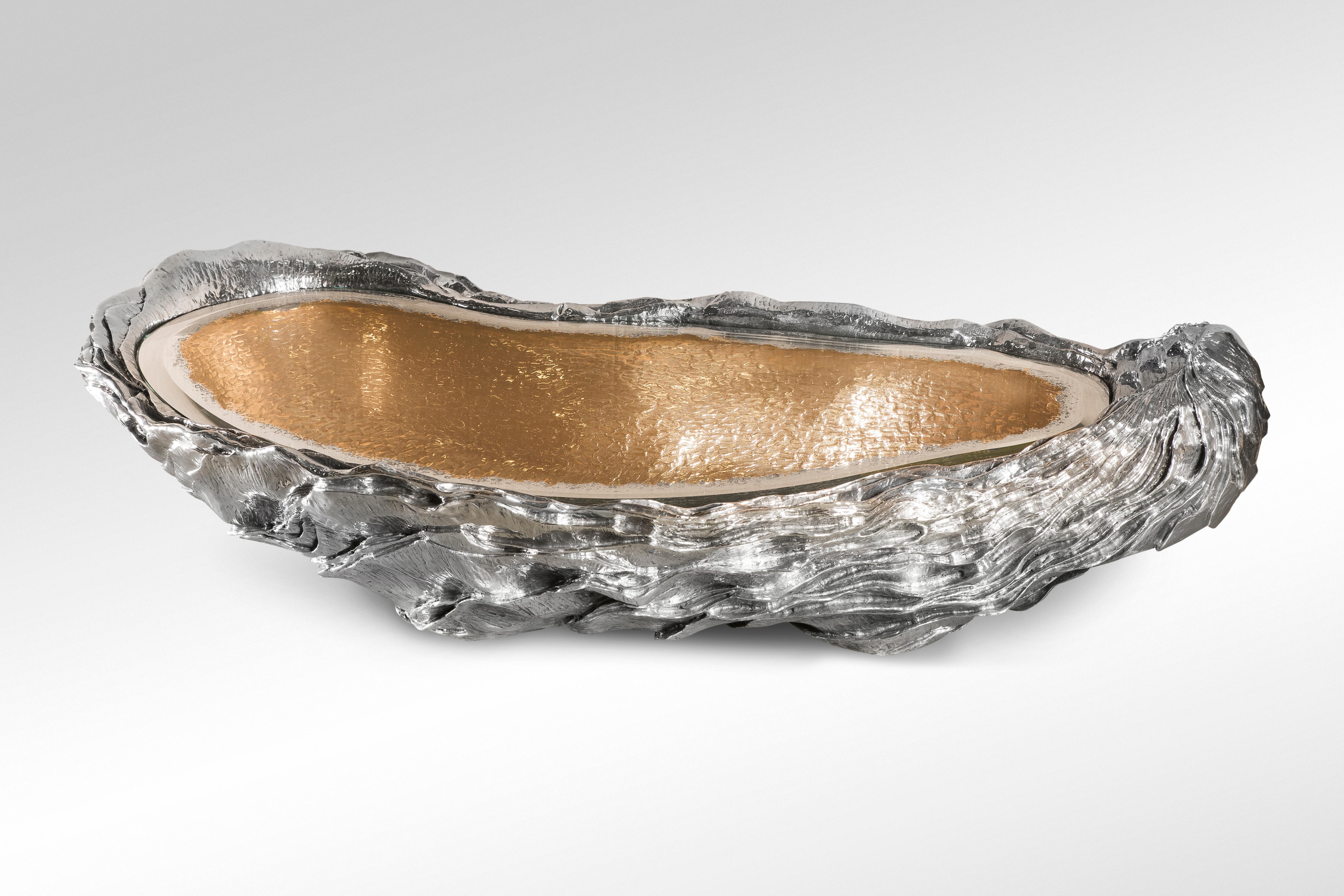Low table made of polished bronze and aluminium with a faceted glass mirror surface.
The oyster, symbolizes a primal connection to our prehistoric past and serves as a poignant reminder of the raw power of nature.

This piece was presented for the
