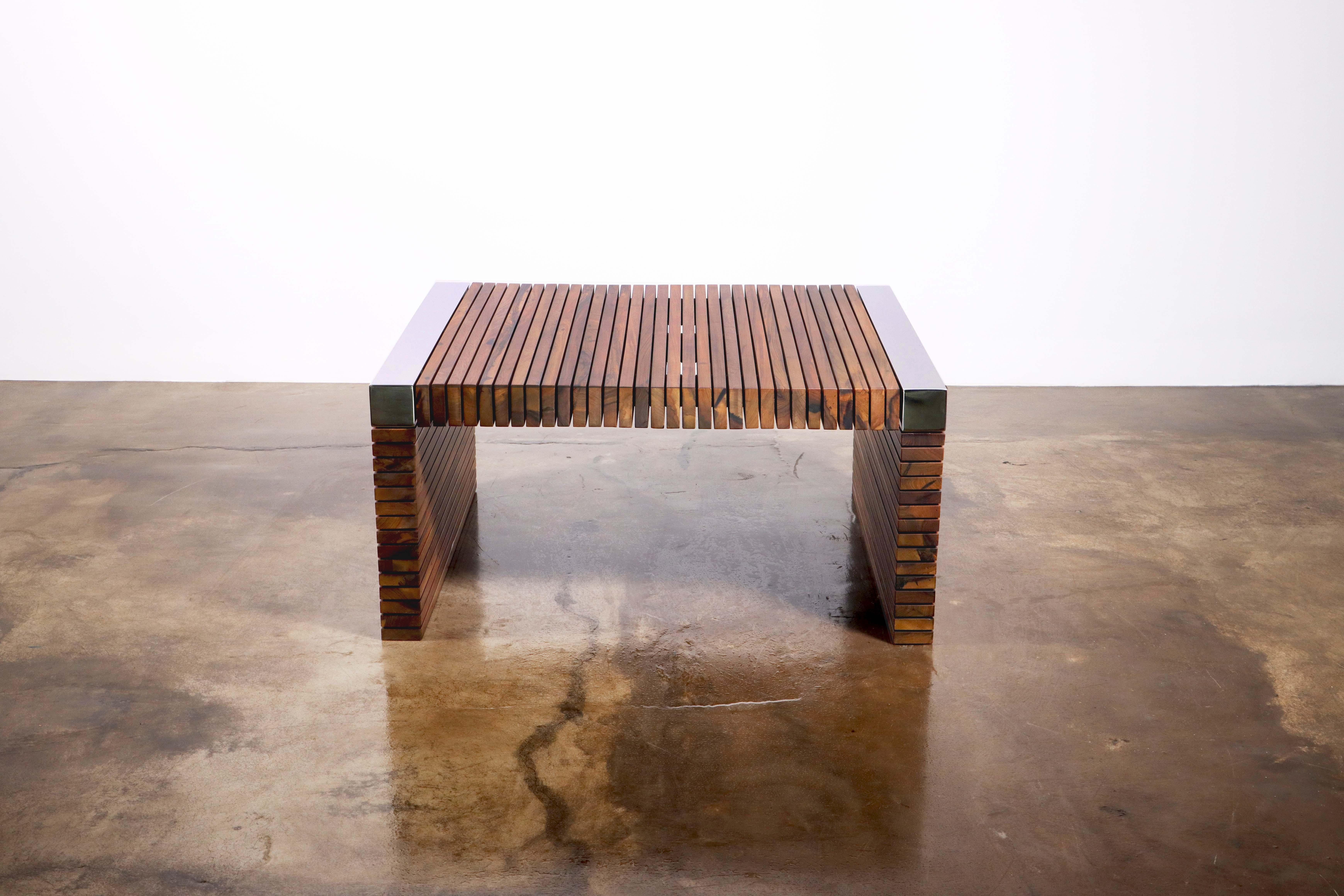 La table Argilla est une étude des contrastes, composée de lattes de bois répétées, suspendues dans l'air par un squelette métallique et des disques qui empêchent les lattes de se toucher. Ses angles sont ornés de barres de métal nickelé poli miroir