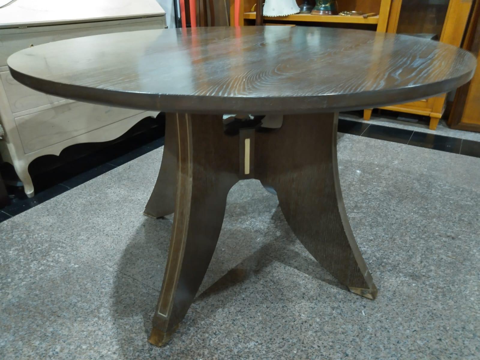 Cette table de salle à manger fabriquée à la main est une élégante fusion d'art et de précision, sculptée dans du chêne massif et enrichie d'incrustations de laiton subtiles mais frappantes. Ses pieds gracieusement incurvés sont encadrés de lignes
