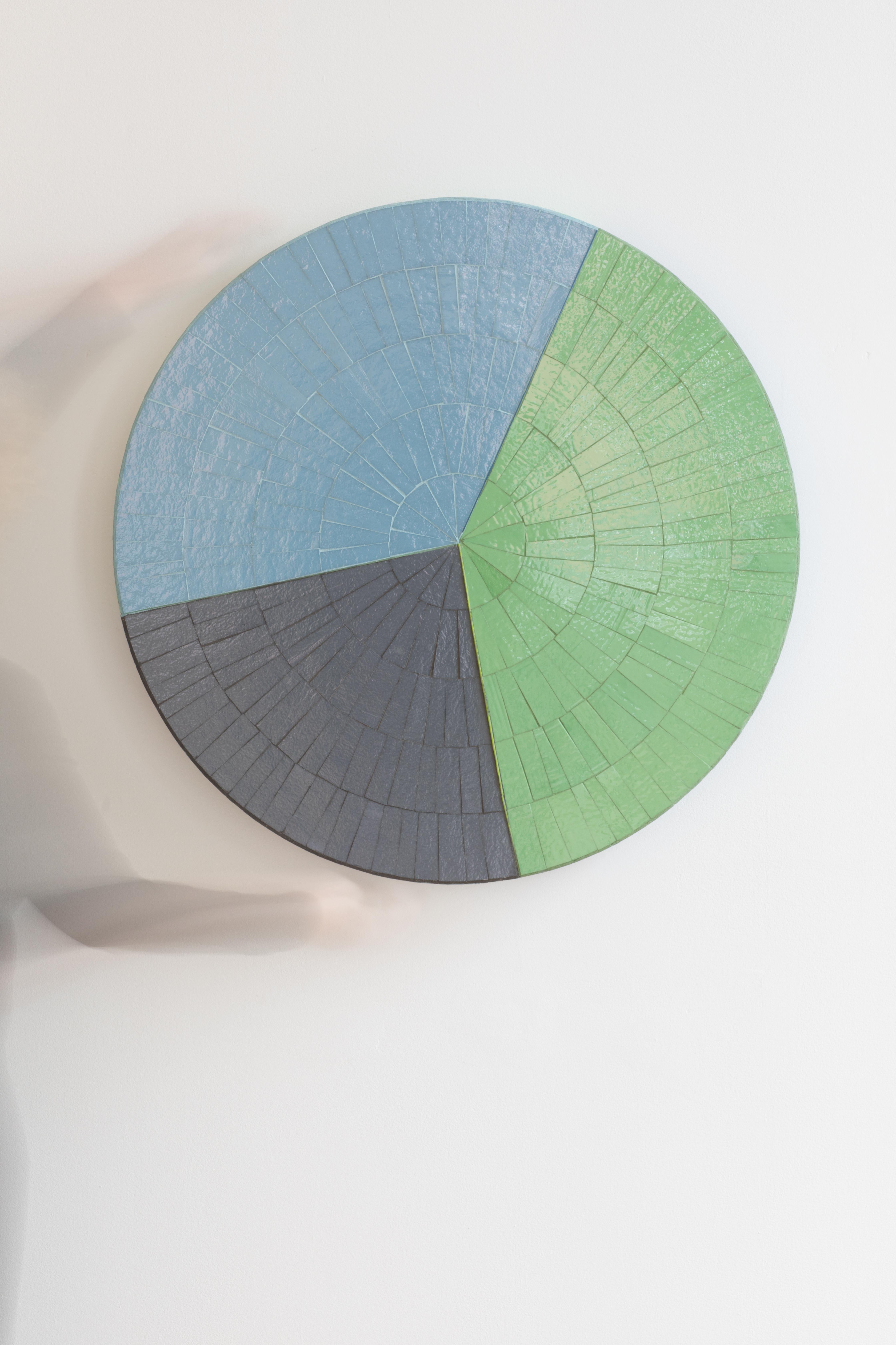 La table basse moderne Color Block d'Ercole Home se compose d'un plateau rond en mosaïque surmontant une base à colonnes fabriquée en érable au fini gris foncé. Le plateau de table en mosaïque à motif Sunburst est disponible dans les couleurs Slate,