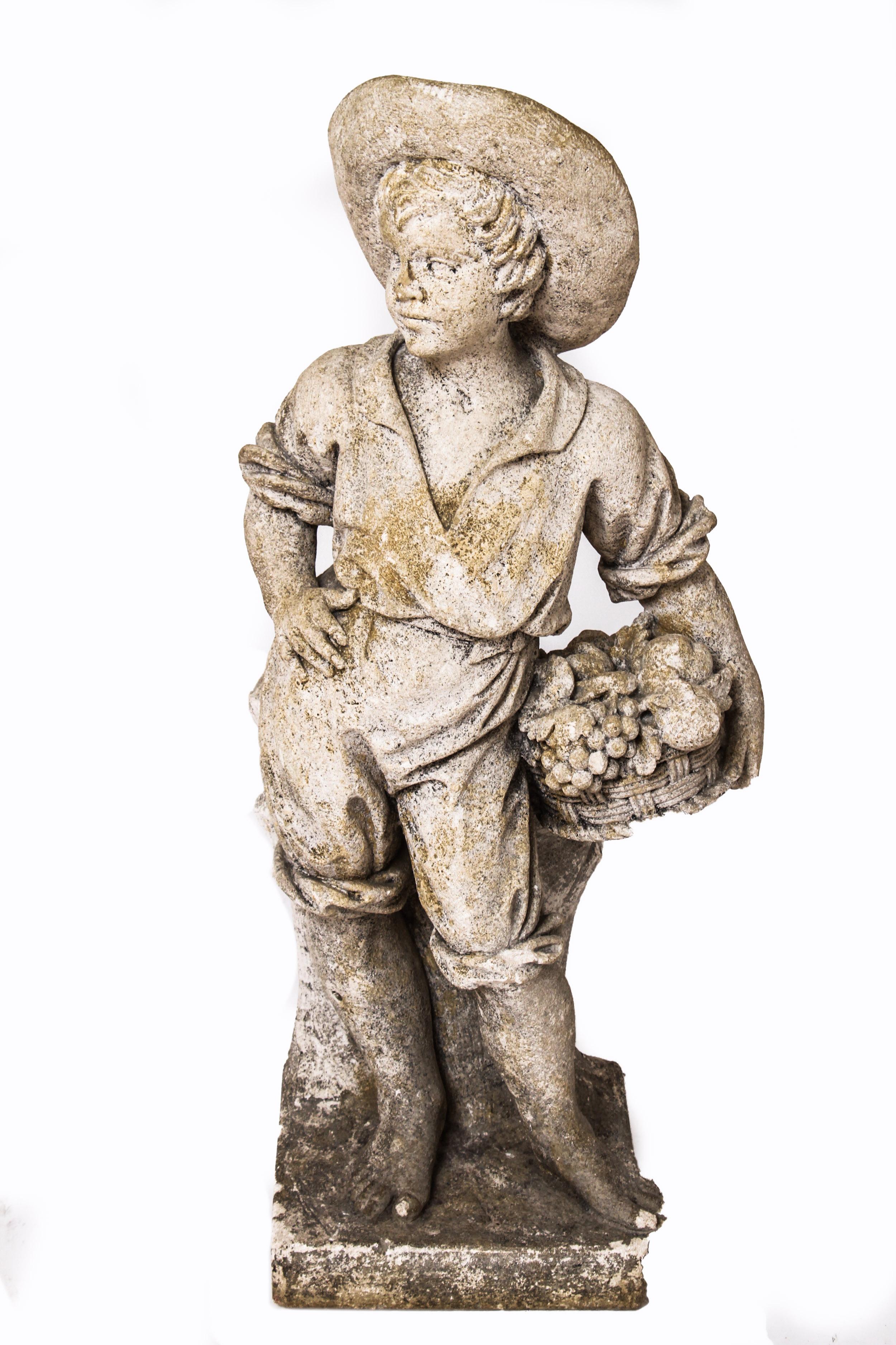 Modern pair of cement garden sculptures depicting two young boys. One boy is holding a basket of fruit and one is holding wheat. The pair is in great vintage condition with age-appropriate wear and use.