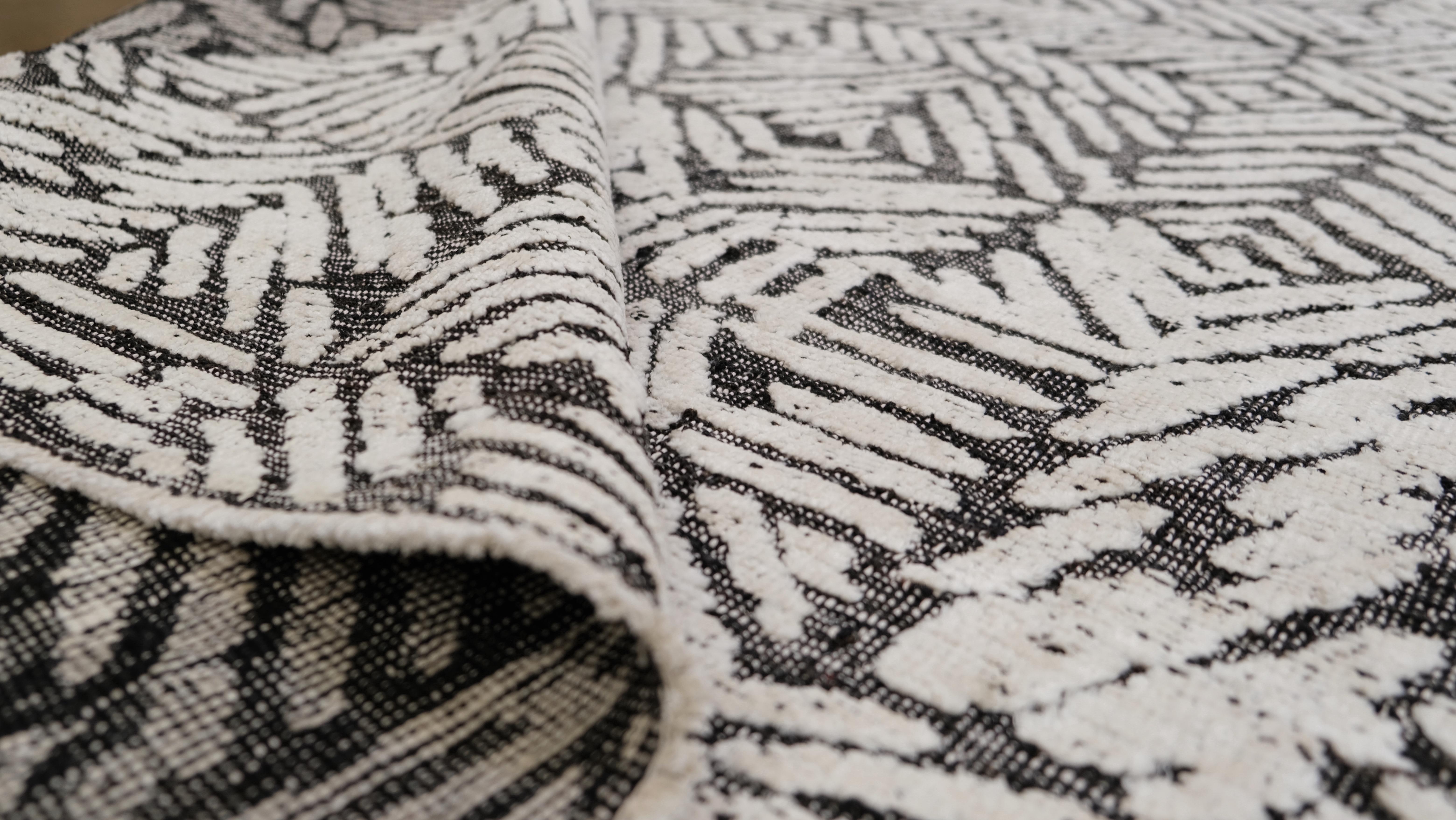Eleva la decoración de tu hogar con esta alfombra contemporánea de lana anudada a mano, con un llamativo diseño geométrico. El diseño intrincado y repetitivo crea un efecto óptico audaz, que lo convierte en una pieza central destacada en cualquier