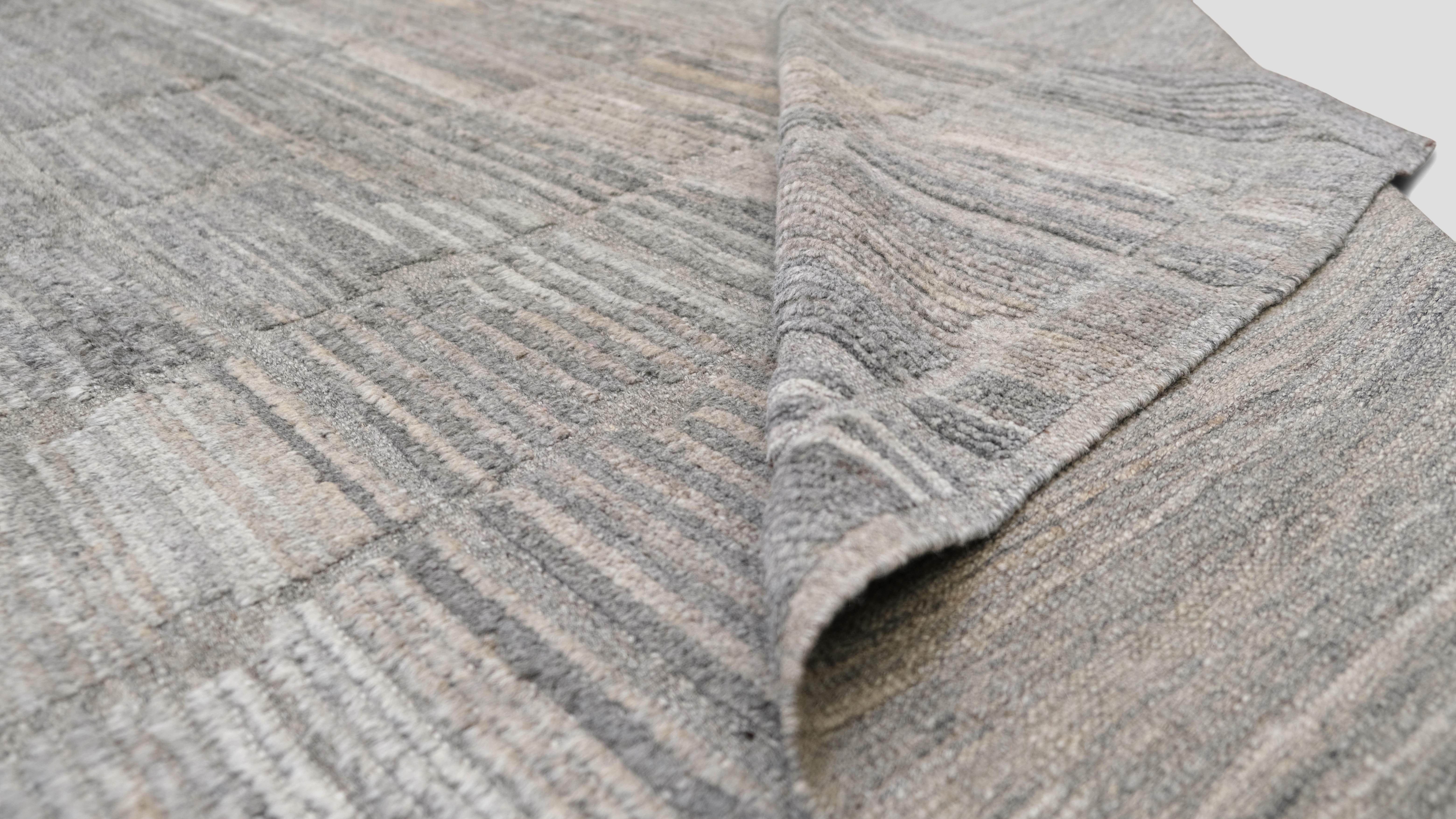 Die schlichte Eleganz dieses handgeknüpften Wollteppichs wertet Ihren Raum auf. Mit einem modernen Gittermuster in einer raffinierten Farbpalette aus gedämpften Grau- und Taupetönen strahlt dieses Stück eine raffinierte, zeitgenössische Ästhetik
