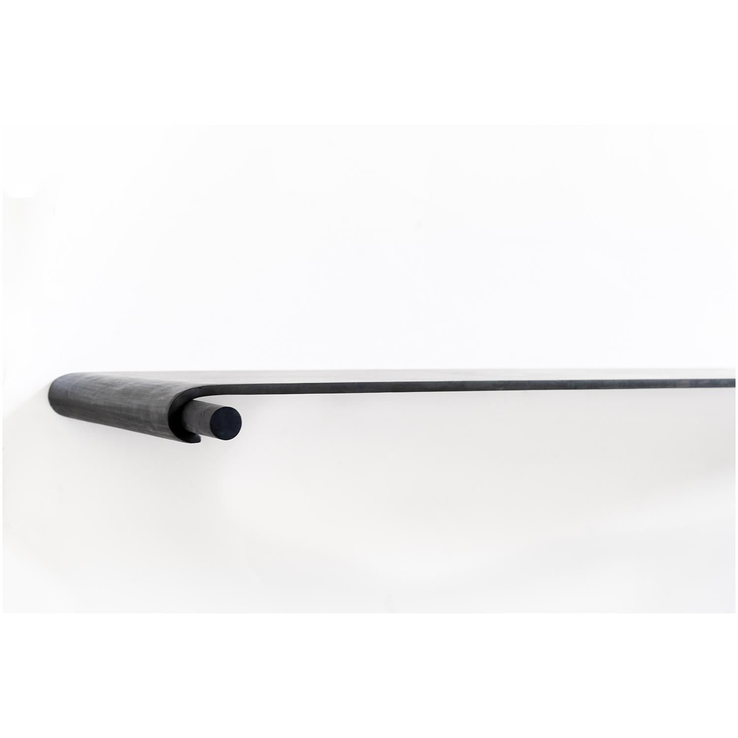 CONSOLE NO. 4 
J.M. Szymanski
d. 2020

A sleek table, bent from a seamless piece of 3/8” thick steel. The table appears to float on a single peg. The table is attached to a wall from the underside of the table.

Custom sizes available. Made in the