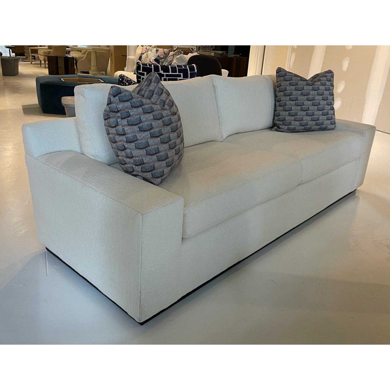 Showroom New. Modern/Contemporary style sofa with wide track arms and clean lines. Complimented with a recessed plinth base. Covered in a white boucle fabric with contrasting throw pillows. Extreme comfort is created with ultra down seat cushions